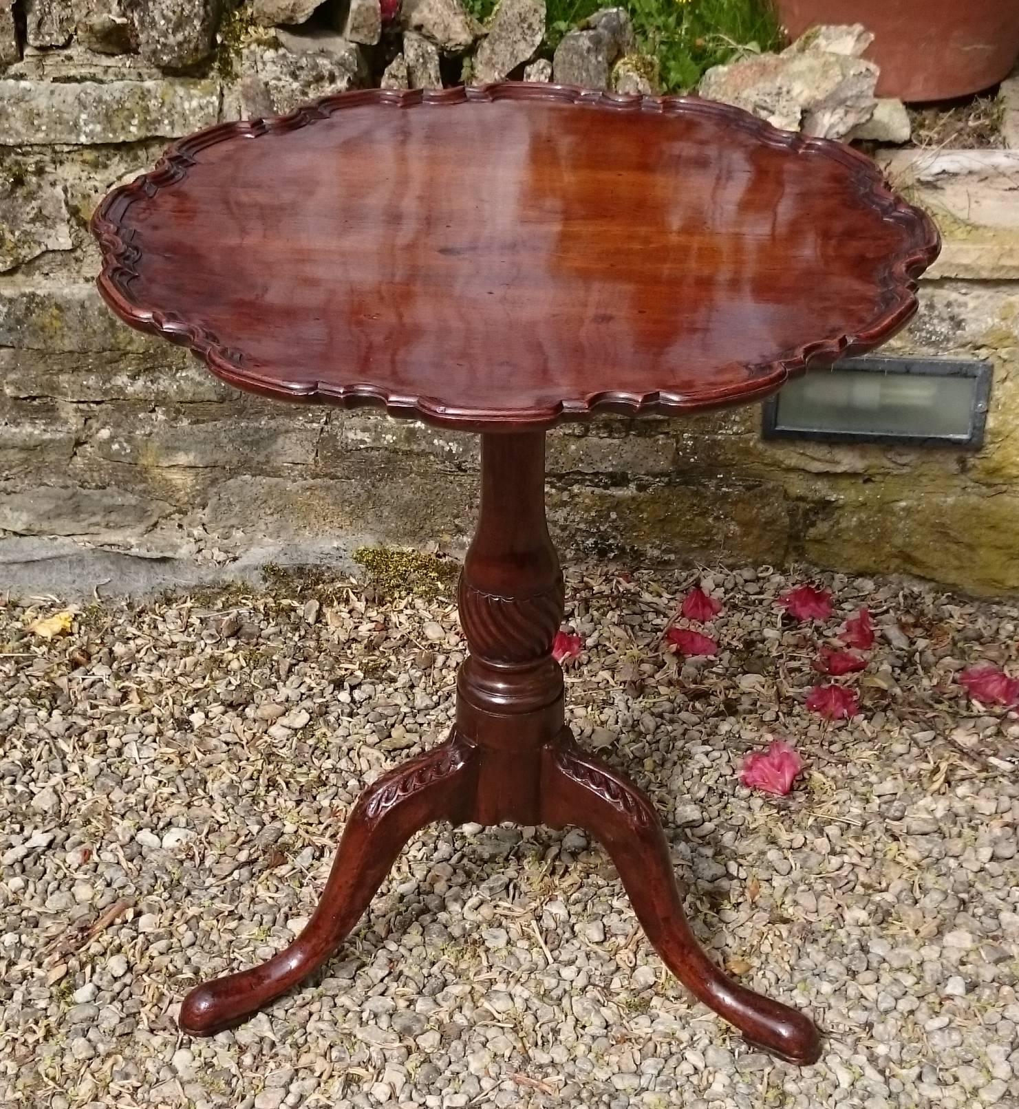 19th century George III revival mahogany antique tripod table. This sort of antique tripod table is sometimes called a wine table, a lamp table, a snap top table, or a small tea table. The edge is generously scalloped and raised above the height of