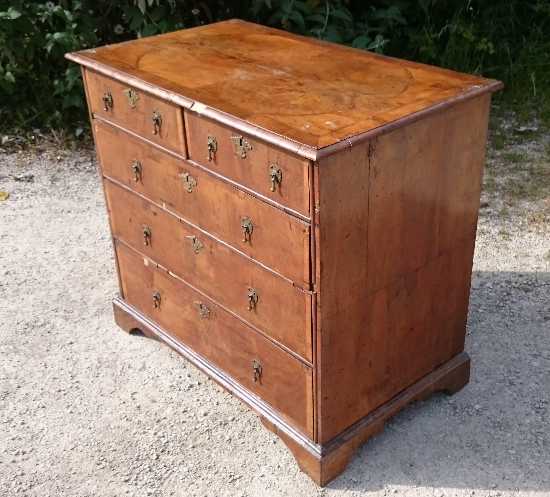 A very fine quality early 18th century walnut chest of drawers. This charming chest of drawers has wonderful quarter cut walnut sides and top comprising four bookmatched quarters to each section. The front and top also have walnut crossbanding and
