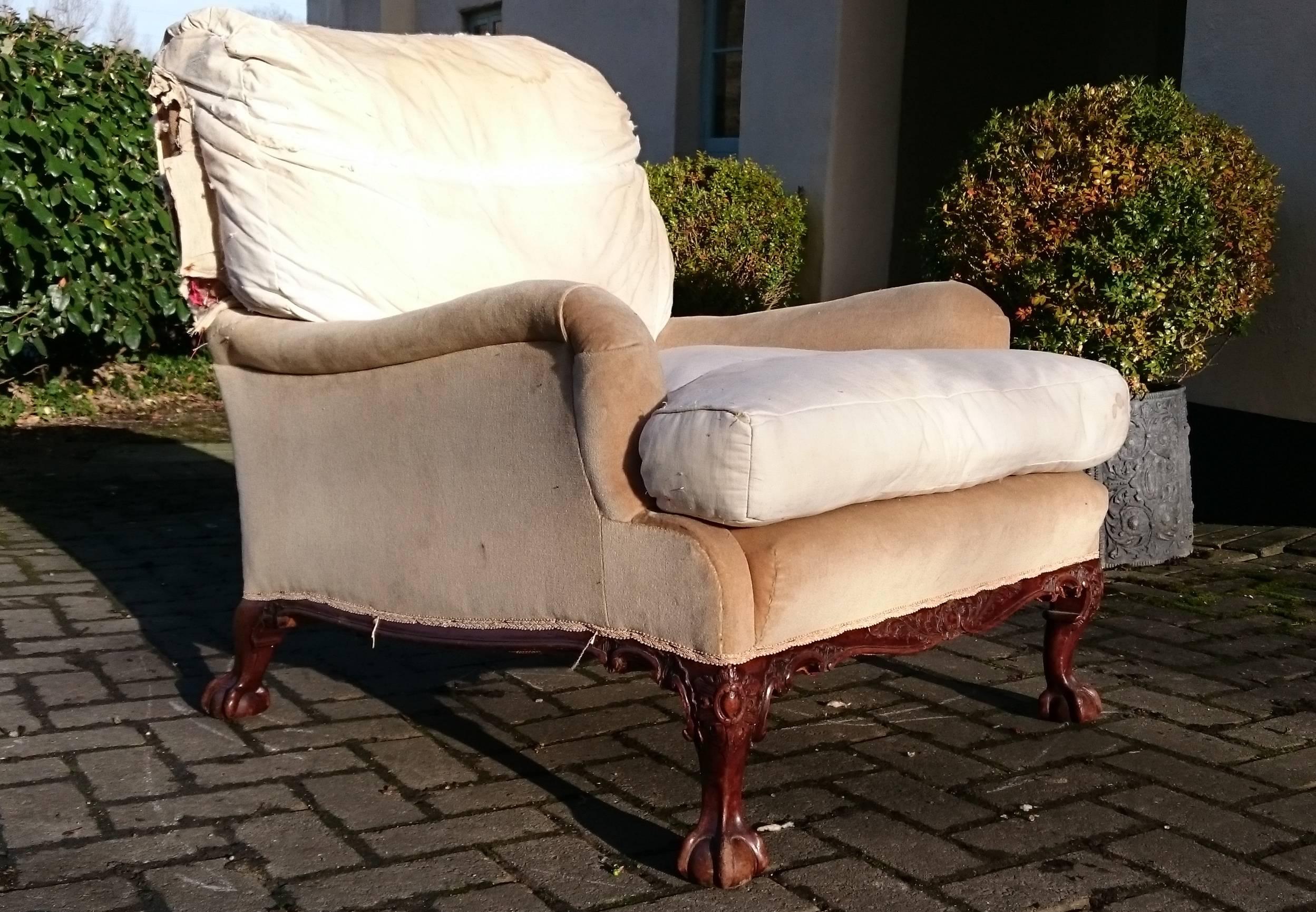 Antique easy armchair made by Howard and Sons of London. This is a special order Grafton model with ball and claw feet and show wood between the legs. Unusually for a Grafton model the base of the chair is serpentine, the lower rail is usually flat