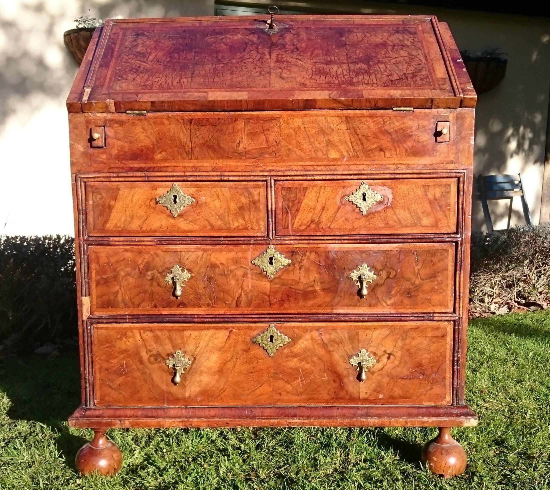 Early 18th century George I period small walnut antique bureau of unusually small-scale standing on four turned bun feet. This is a charming bureau which really shows off the pre-mahogany era of furniture making very well. It has feather banding