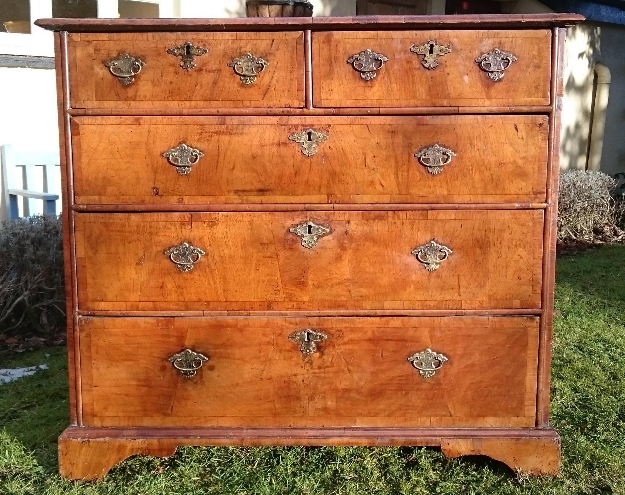A very fine quality early 18th century walnut chest of drawers. This charming chest of drawers has wonderful quarter cut walnut sides and top comprising four bookmatched quarters to each section. The front and top also have walnut cross banding and