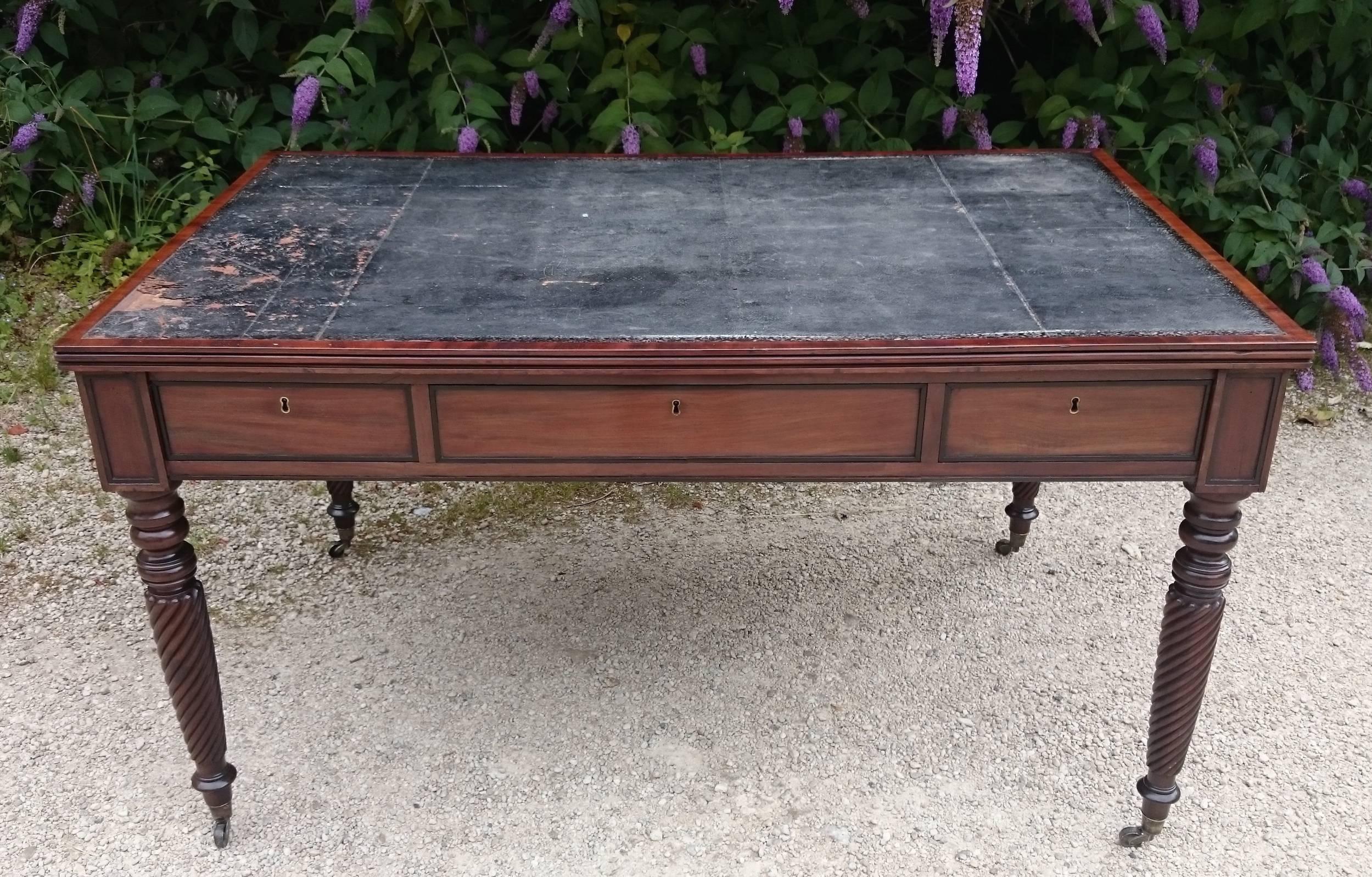 Antique Regency period mahogany library table or writing table standing on turned legs with brass casters and caps and rope twist decoration typical of the Regency period. This is a useful desk as it is unusually high for the period which makes it