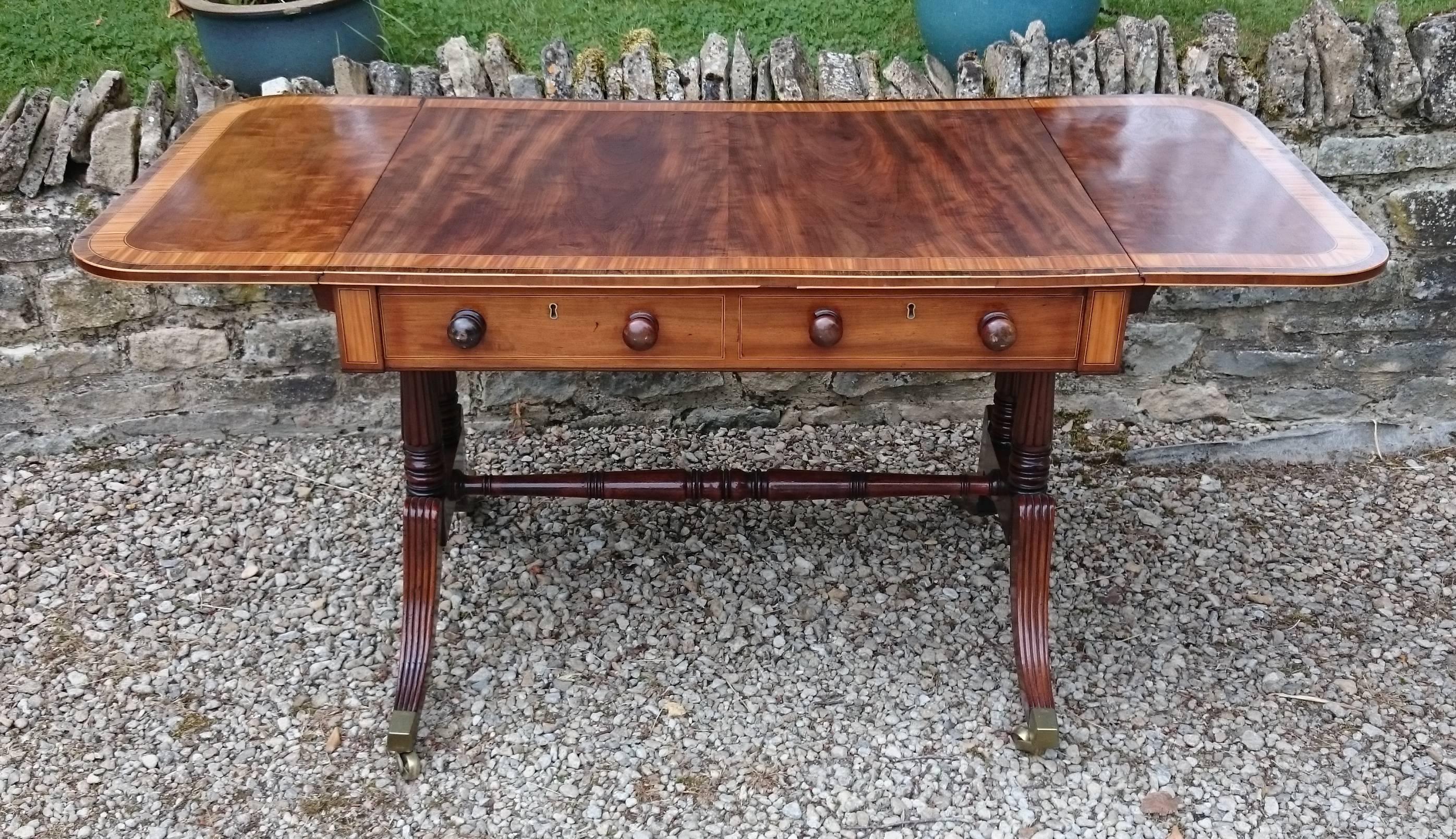 Exceptional quality Regency antique sofa table made of a particularly fine cut of fiddleback mahogany with stringing made of box and ebony woods and with cross banding made from a very dense grained and well figured cut of expensive satin wood.