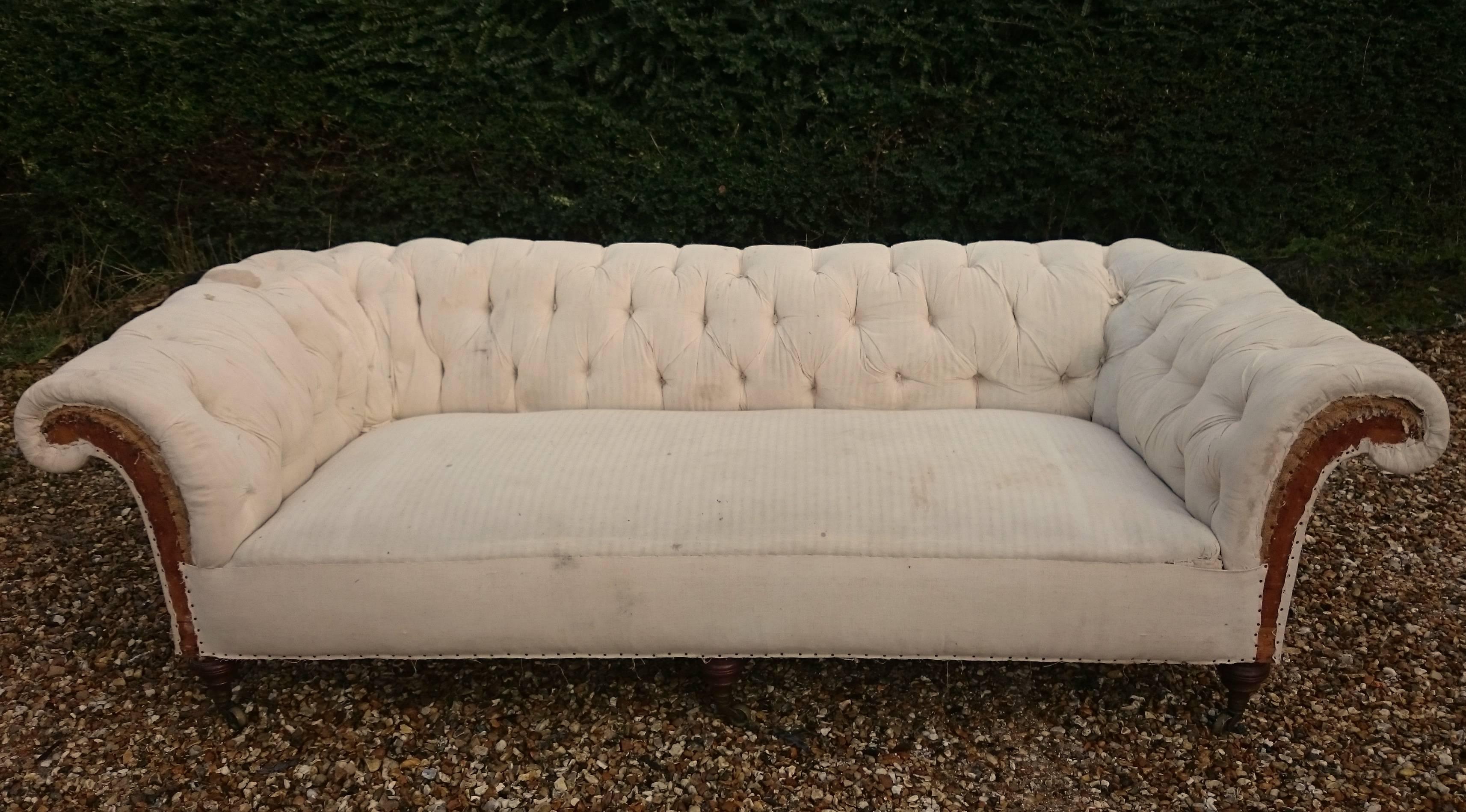 Absolutely massive Howard and Sons Chesterfield sofa with three turned Howard legs on the front and unusually with three frame legs on the back. The stamp on the caster would indicate the sofa was made before 1890, and judging by the overall shape