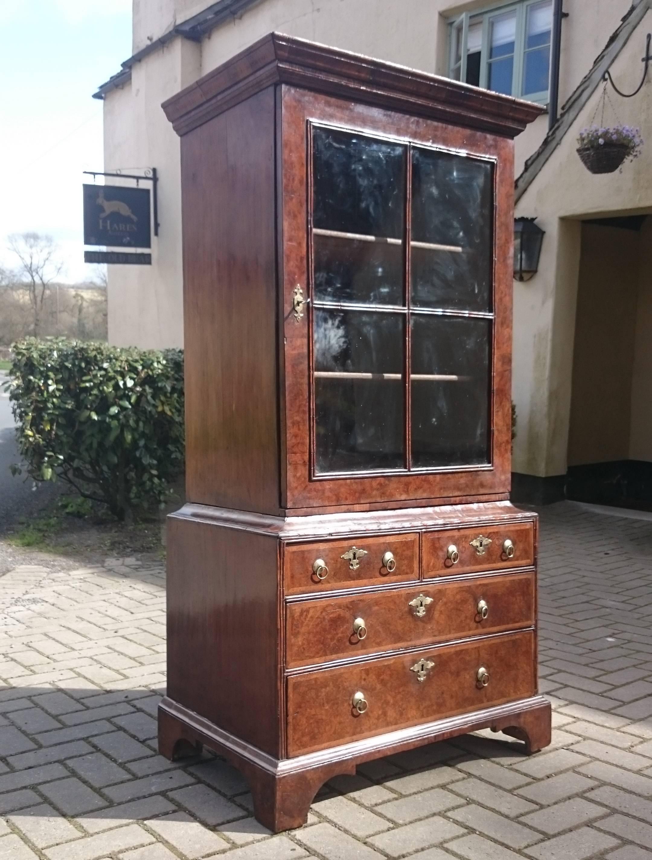 Early 18th century walnut cabinet or bookcase. This bookcase is made of burl walnut quarter cut veneer with feather banding around the drawers and pre-cockbeading double molded edge around the drawers and glazing. This is a very tactile piece of