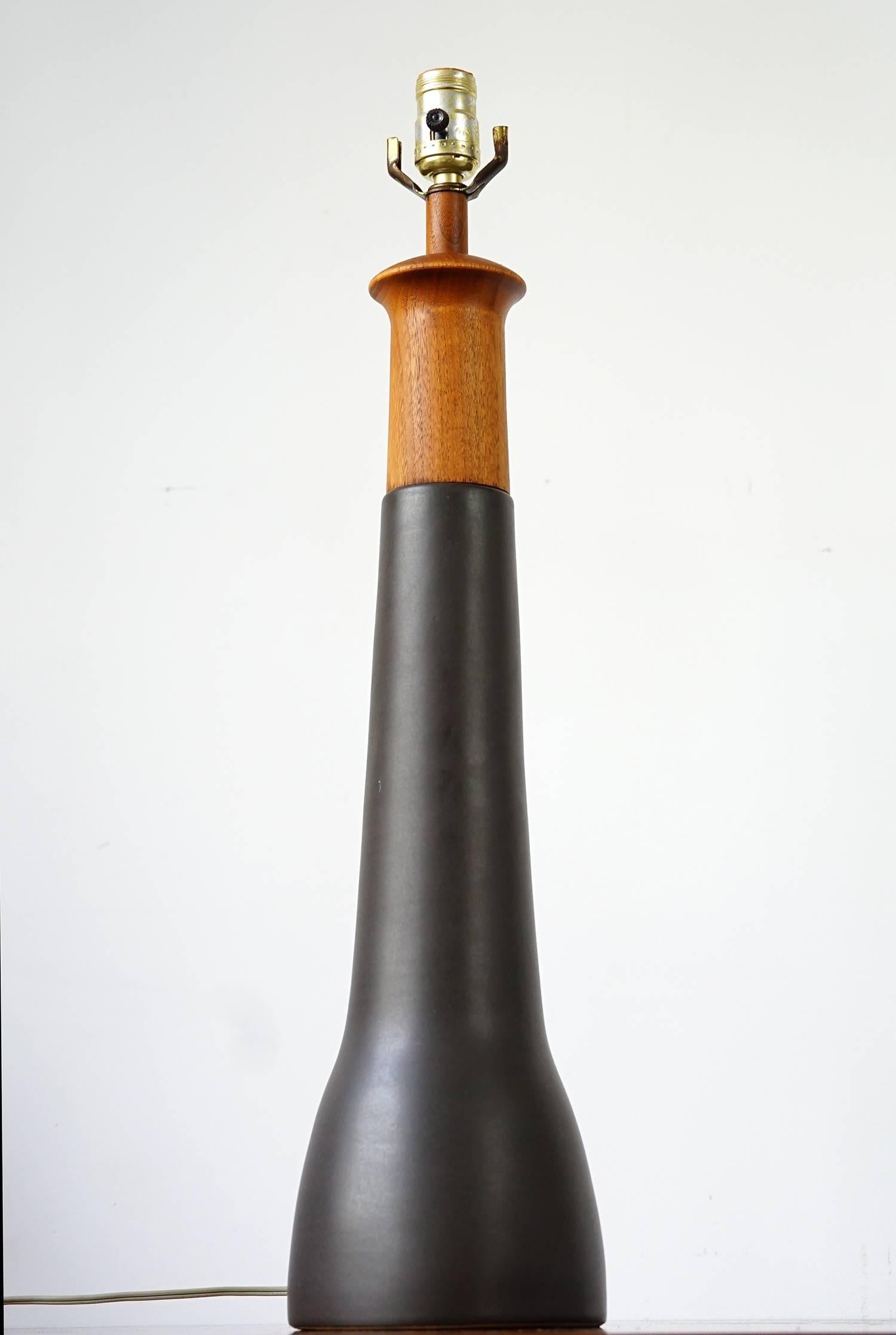 Tall, graceful form in graphite-toned ceramic with contrasting teak top. Original shade is in exceptional condition for its age with minor signs of wear. Original cylindrical, teak finial. Signed. A handsome example.

Overall Dimensions including