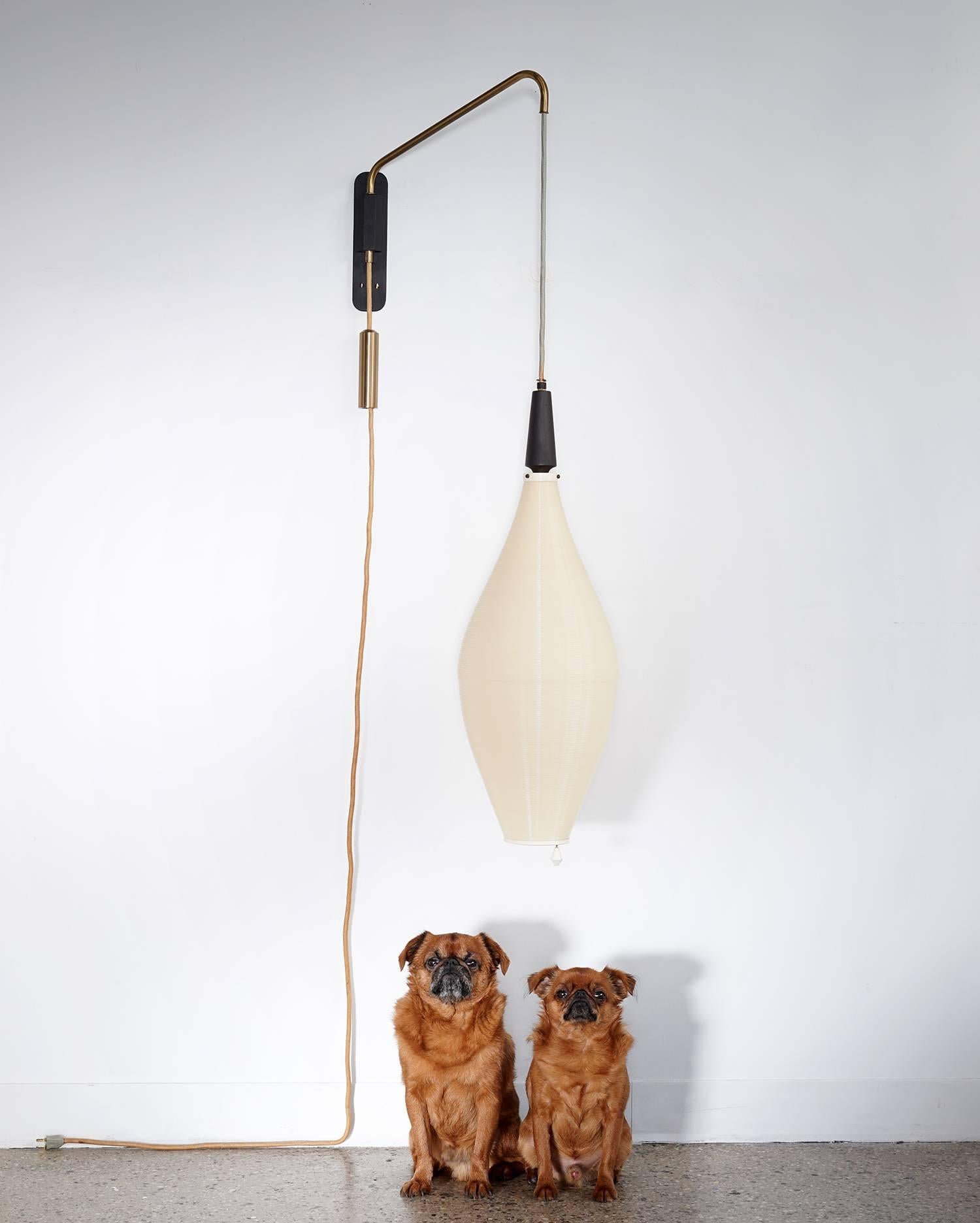 Large-scale light in great, all original condition. The adjustable height shade is suspended from a brass extension arm with swing movement and is balanced by a heavy cylindrical brass counter weight. The cream plastic tones and brass hardware are