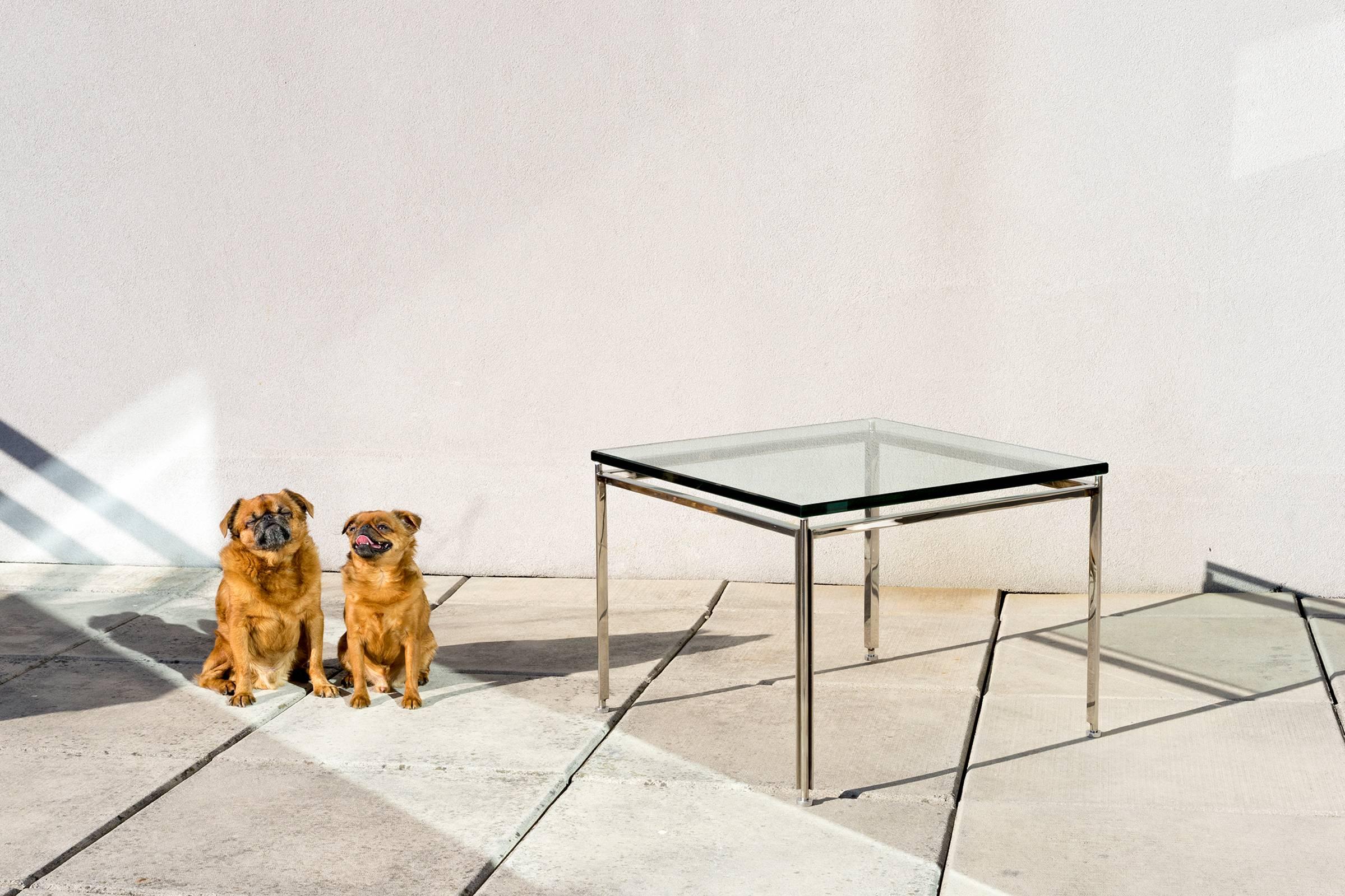 Versatile; functions well as a side or cocktail table. Lightweight yet sturdy steel base with bright, polished metal finish. Original, height-adjustable feet. Three quarter inch glass top floats above frame for a lightweight, airy effect. Clean and