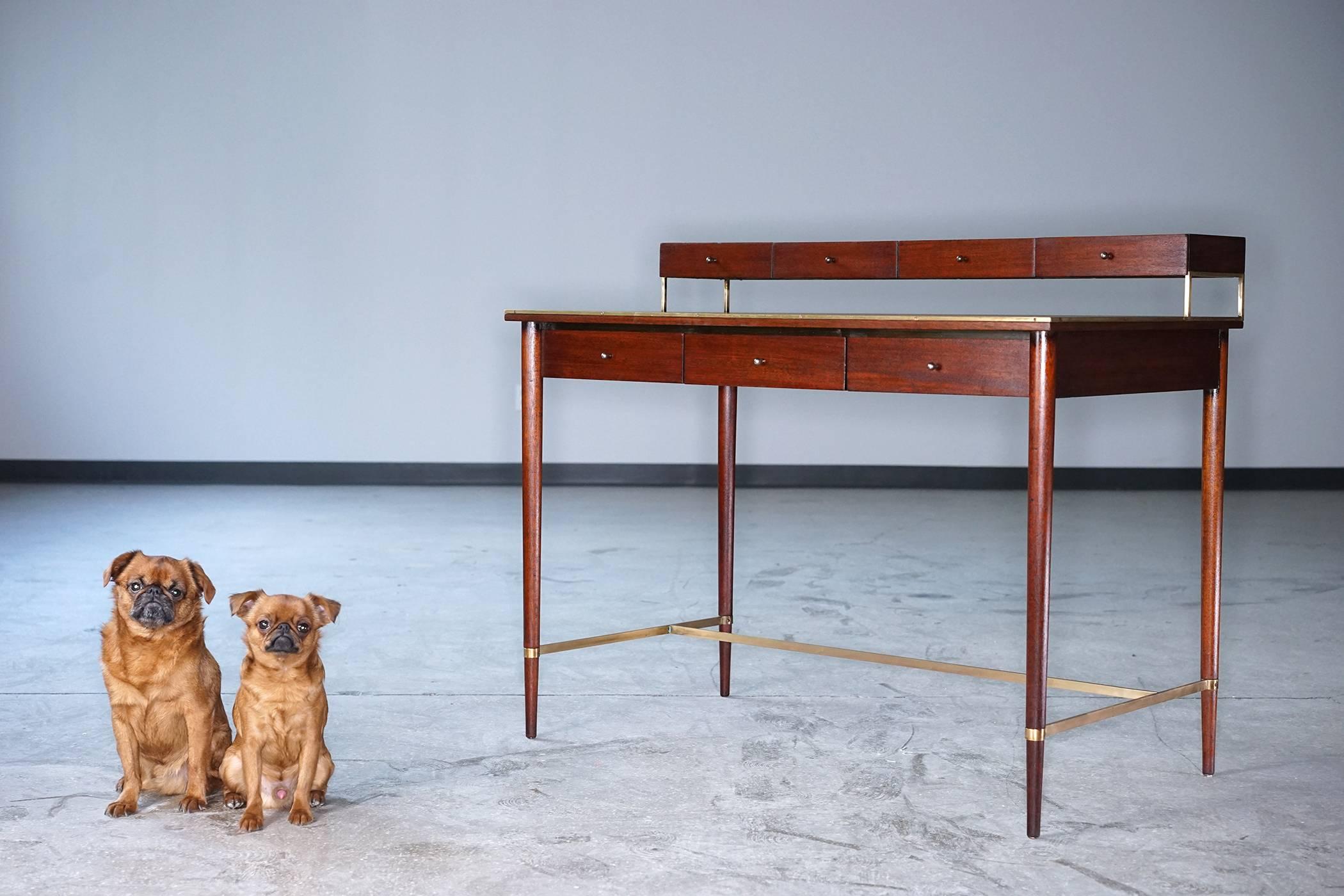 Elegant mahogany desk with long, tapered legs and polished brass details. Seven drawers. Presentable from every angle. Fine refinished condition with rich, warm tone.

Additional dimension:
24.87