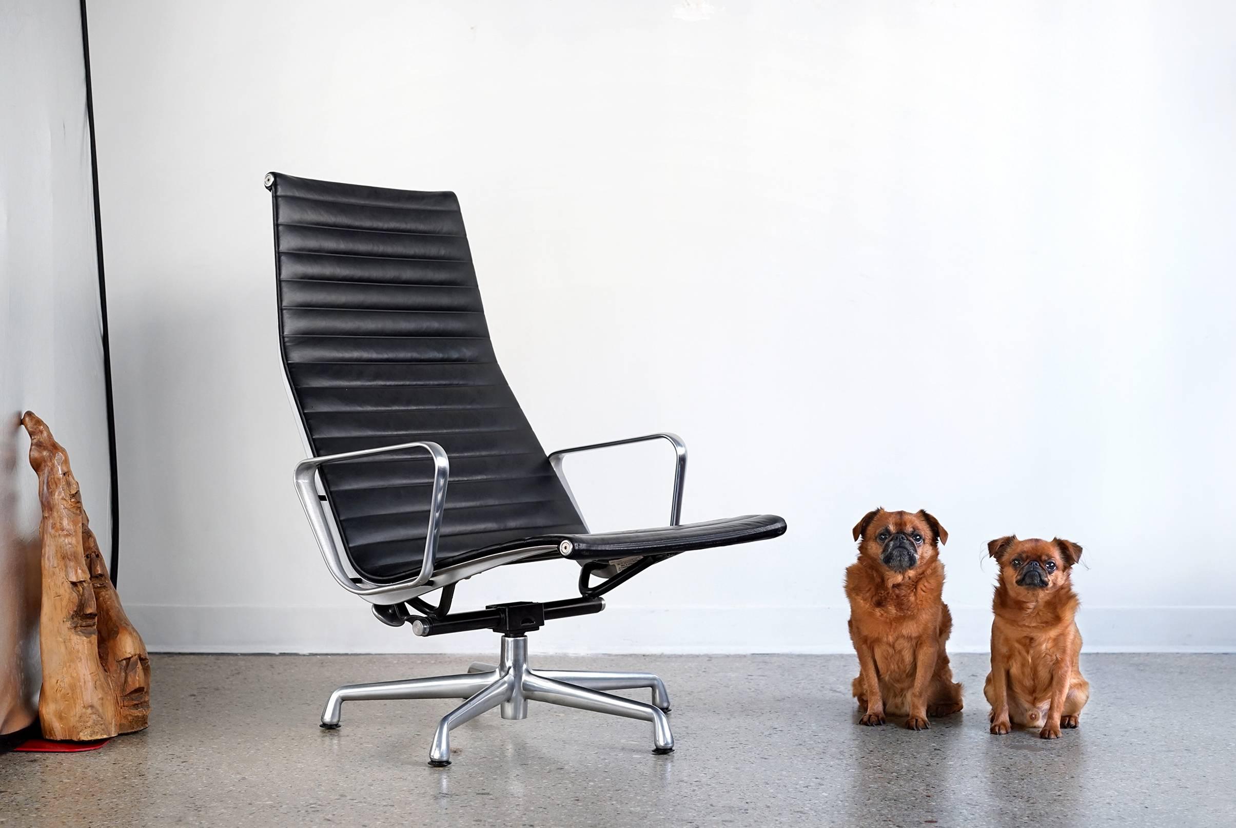 We have here a fine example of Eames' Aluminum group chair featuring black, leather upholstery, high back, and five star base with original black, plastic feet. Classic, handsome, and exceptionally comfortable. The attached headrest flips back and