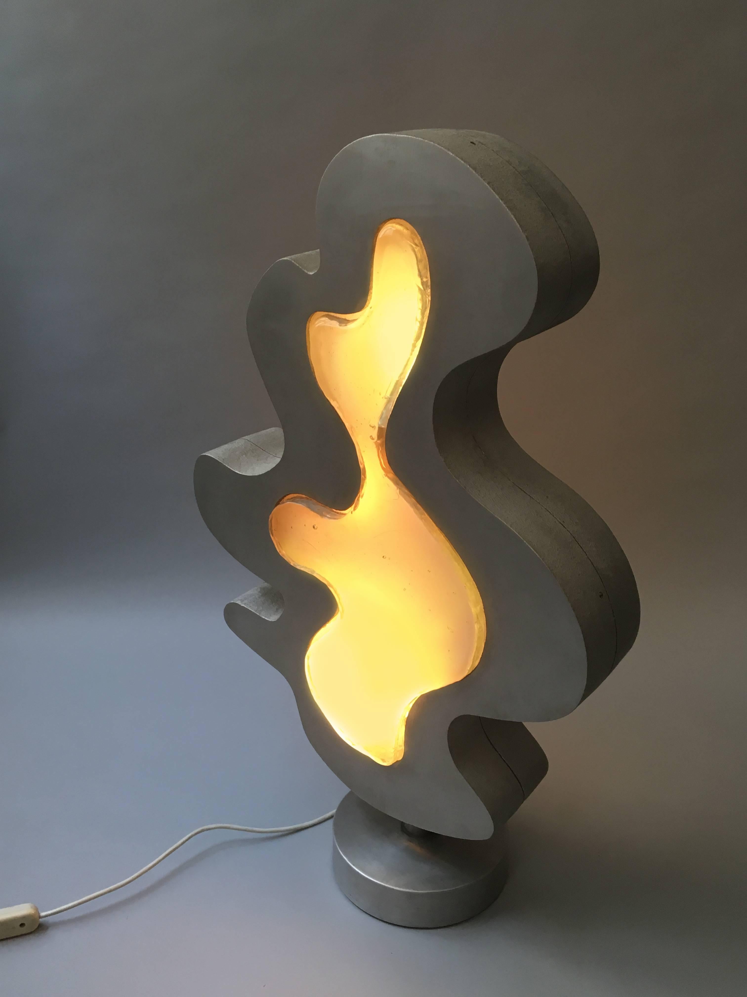 The Vegnusca light is part sculpture and part functional floor light. It is composed of two biomorphic shaped cast aluminum frames, two molded glass inserts and five internal lightbulb sockets. The cylinder shaped base is made of iron and cast