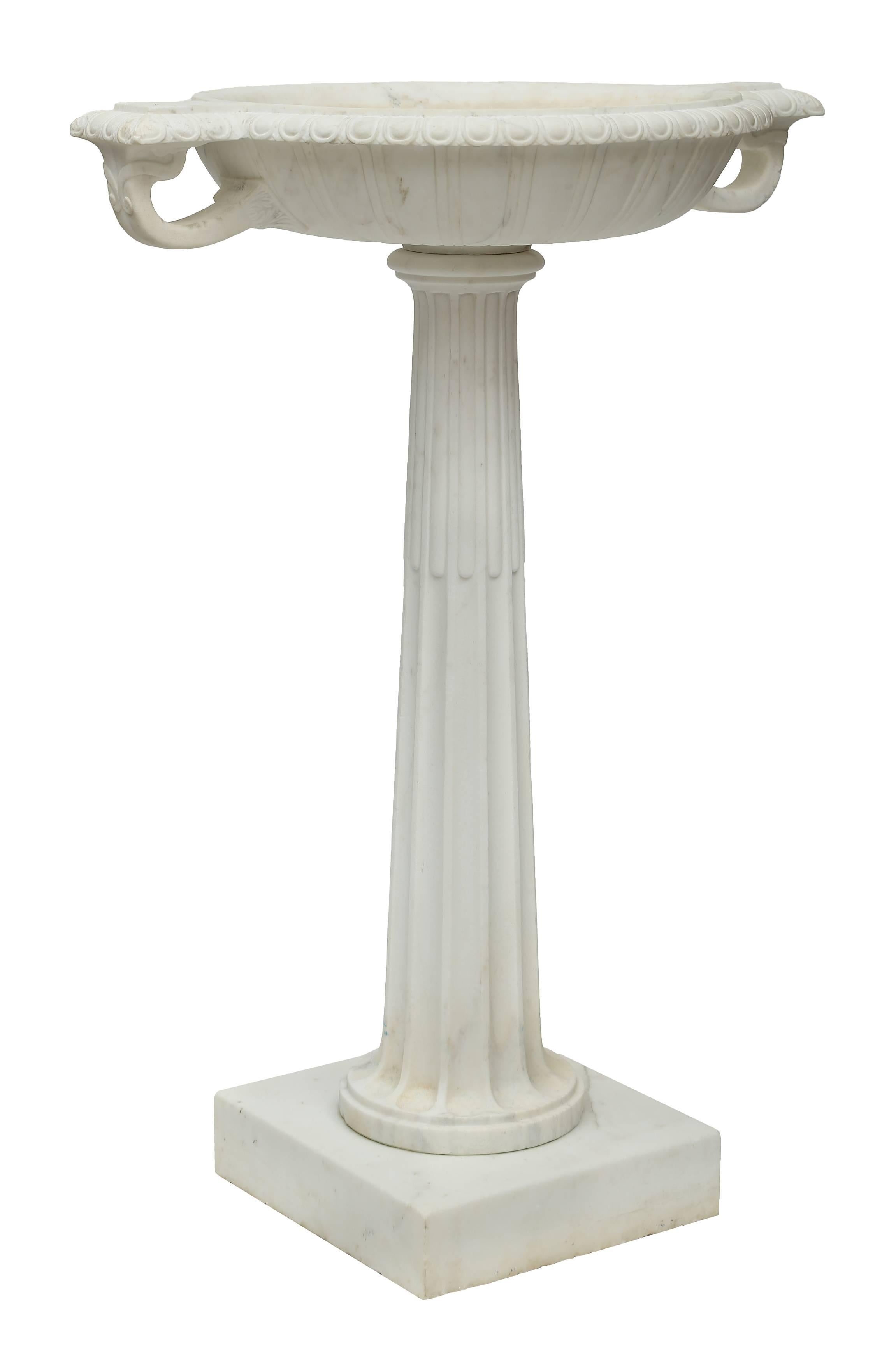 A superb Italian 19th century neoclassical style white Carrara marble bird bath. This elegant bird bath is raised on a solid square white Carrara marble base. Above is the tapered fluted and reeded column. At the top is the wide tazza designed oval