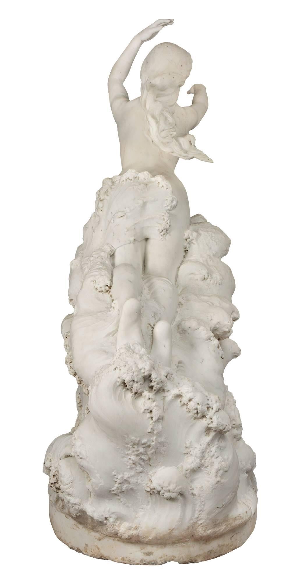 A magnificent and very unique and high quality, French, 19th century white Carrara marble statue, signed E. Damé, 1892. A nude sea nymph rising out of the ocean waves. Her arms elegantly raised with her long tresses windswept and a beautiful