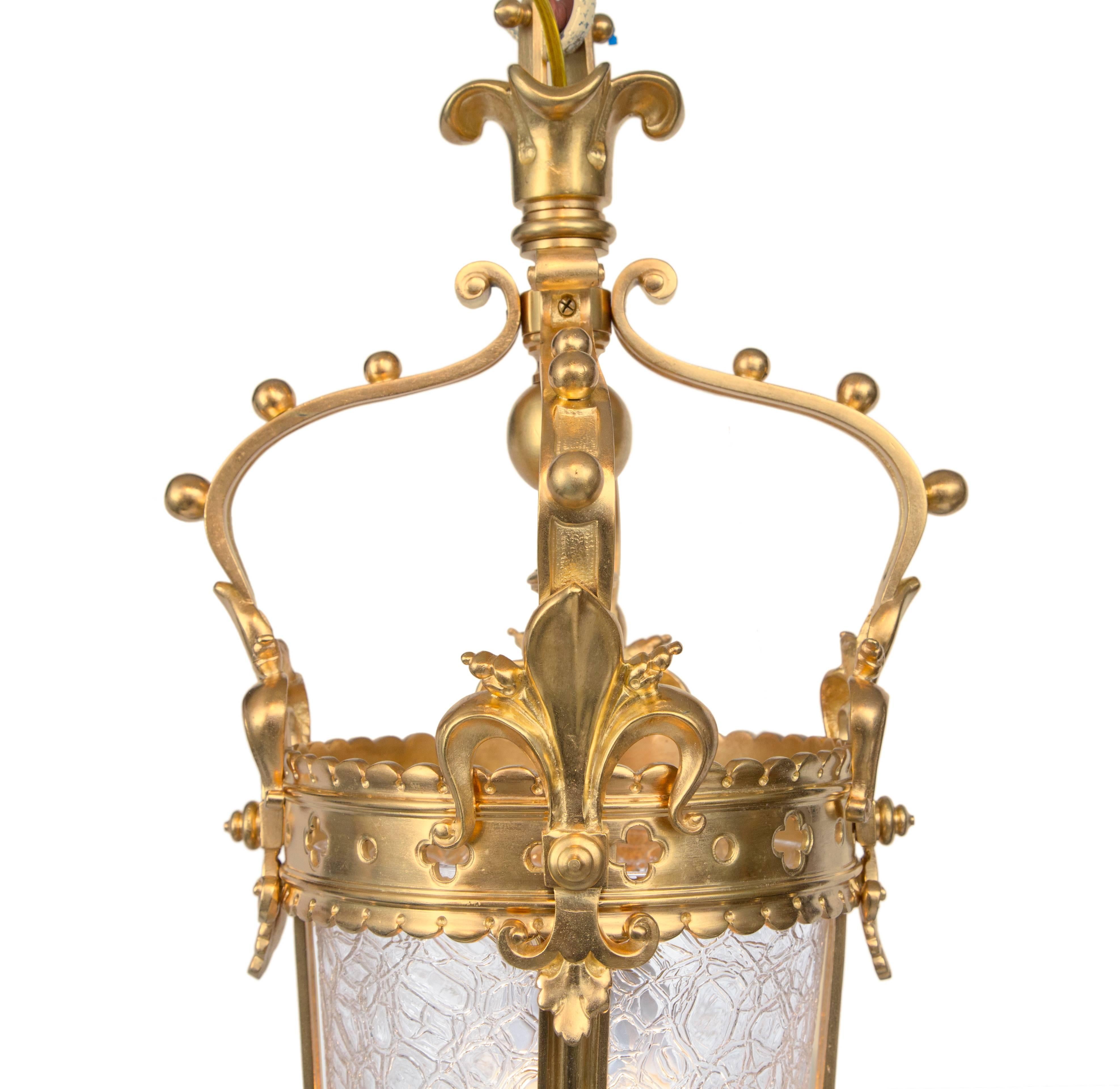 An elegant and small-scale French 19th century Renaissance style ormolu and glass lantern chandelier. The lantern is centered by a most decorative pierced bottom inverted finial. Four lightly curved supports encase the central textured glass and
