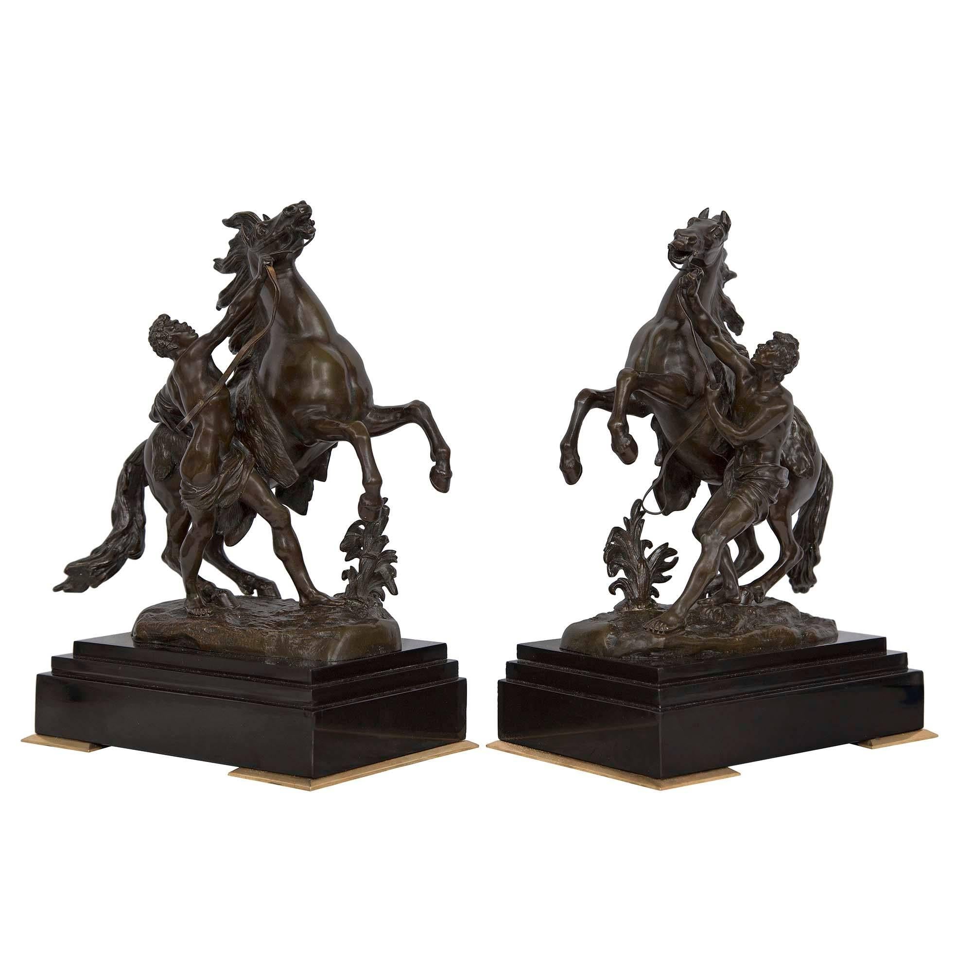 A most impressive true pair of French 19th century patinated bronze Marly horses. Modeled after the Chevaux de Marly by Guillaume Coustou outisde Le Palais de Versaille. The wonderfully detailed stallions are rearing and handled by richly sculpted