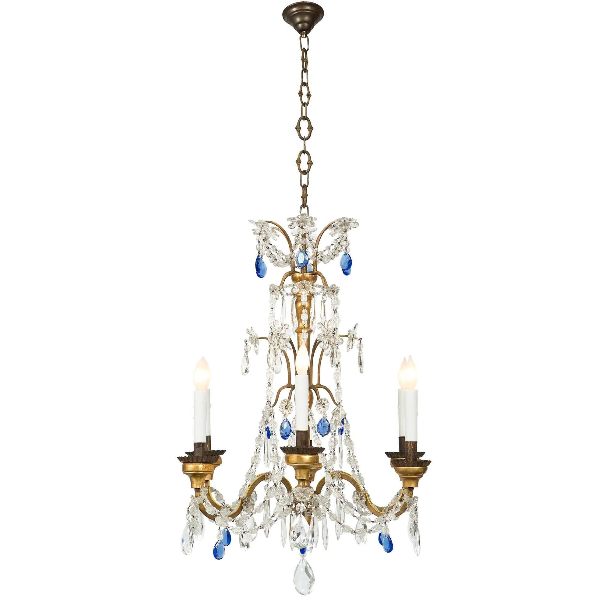 A charming Italian 18th-century giltwood, gilt metal and glass six light chandelier. The chandelier with 6 electrified ’S’ scrolled metal arms leading to giltwood candle cups and ridged patinated metal saucers. The arms are decorated with glass