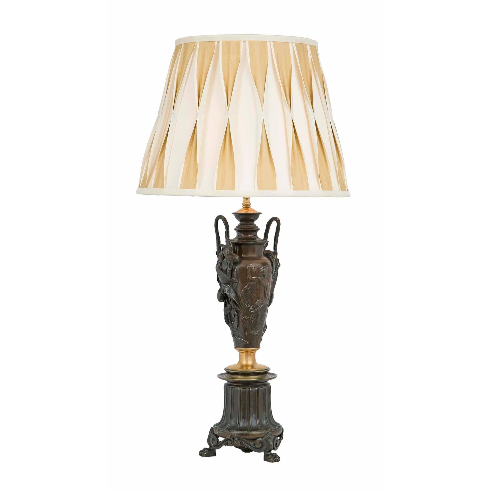 A stunning true pair of French 19th century Neo-Classical st. patinated bronze and ormolu lamps. Each lamp is raised by handsome paw feet below a circular mottled base and ormolu band. The fluted bronze center pedestals are decorated with olive