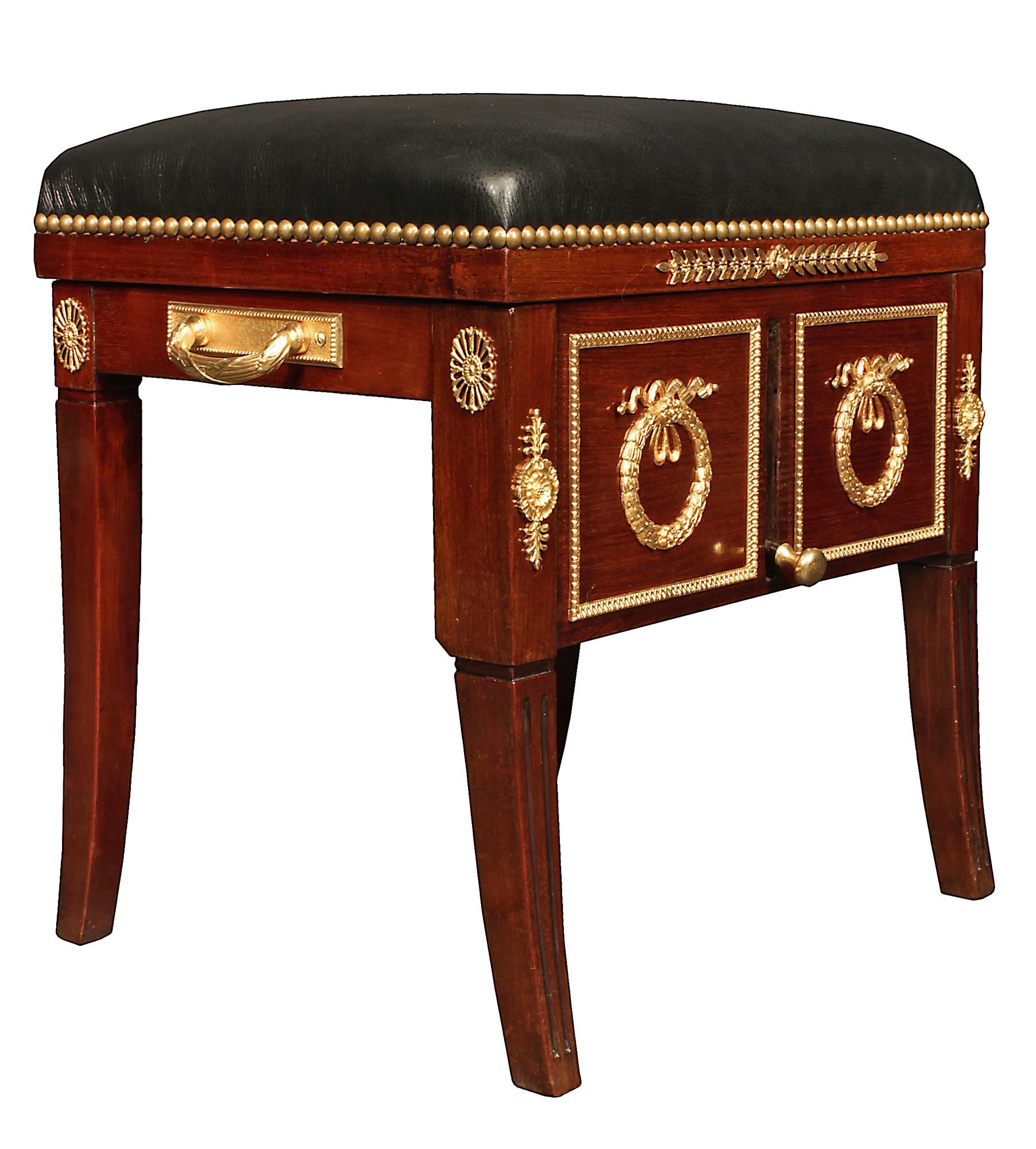 A remarkable French 19th century Neo-Classical st. mahogany and ormolu piano bench. This adjustable mechanical bench is raised on fluted legs accented with pierced ormolu mounts at the top and sides. At the front are large ormolu wreaths and bows