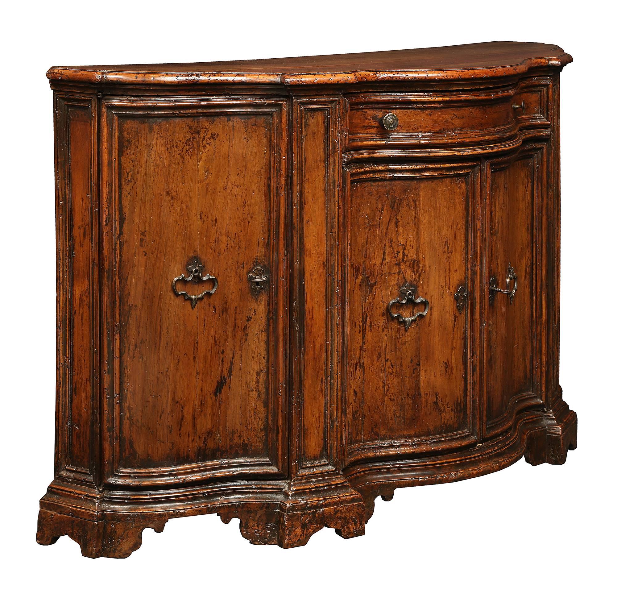 An extremely handsome Italian 18th century walnut Venetian buffet. This wonderful bombée shaped buffet is raised on a solid scrolled base with stepped frieze. Two doors below a drawer are centered between larger curved doors at each side. The doors