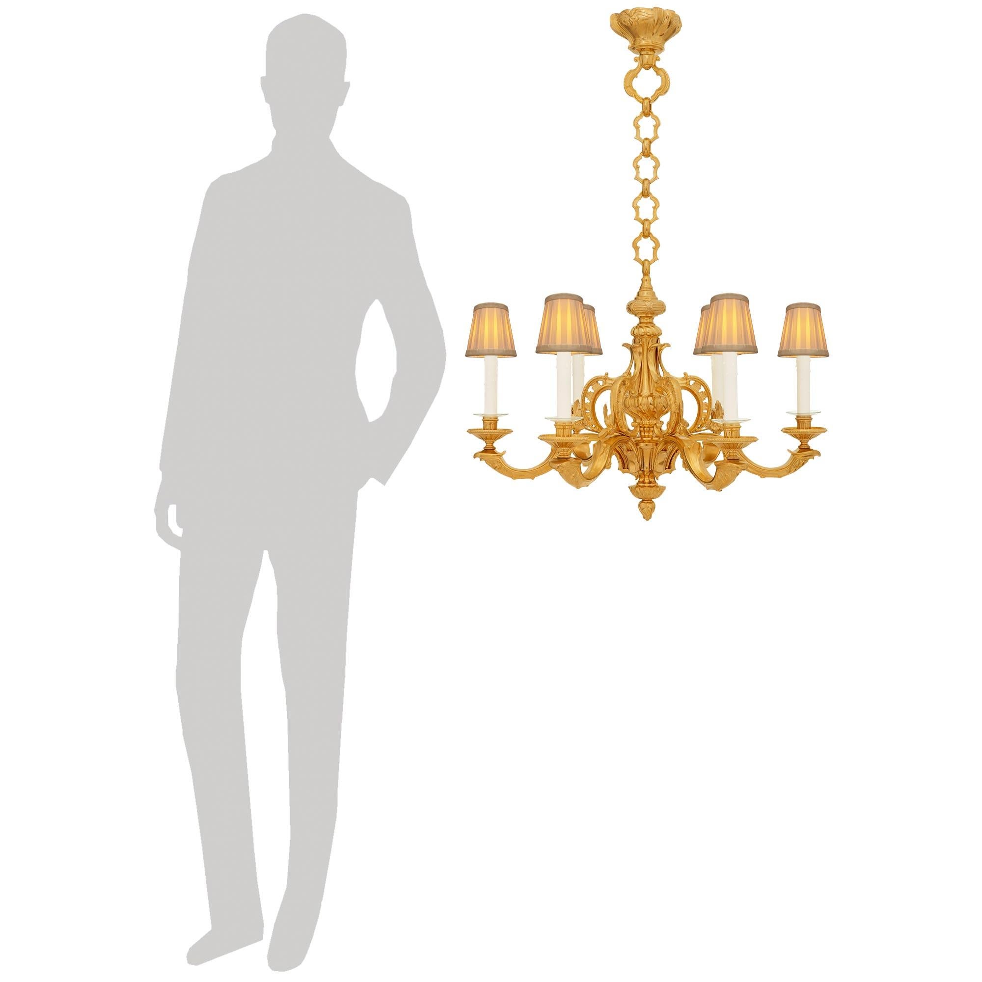 An elegant and high quality French late 19th century Louis XV/XVI st. Ormolu chandelier. This stunning six arm chandelier is centered by a charming spiral reeded final below the Ormolu base to which the six arms are connected. Each scrolled arm is