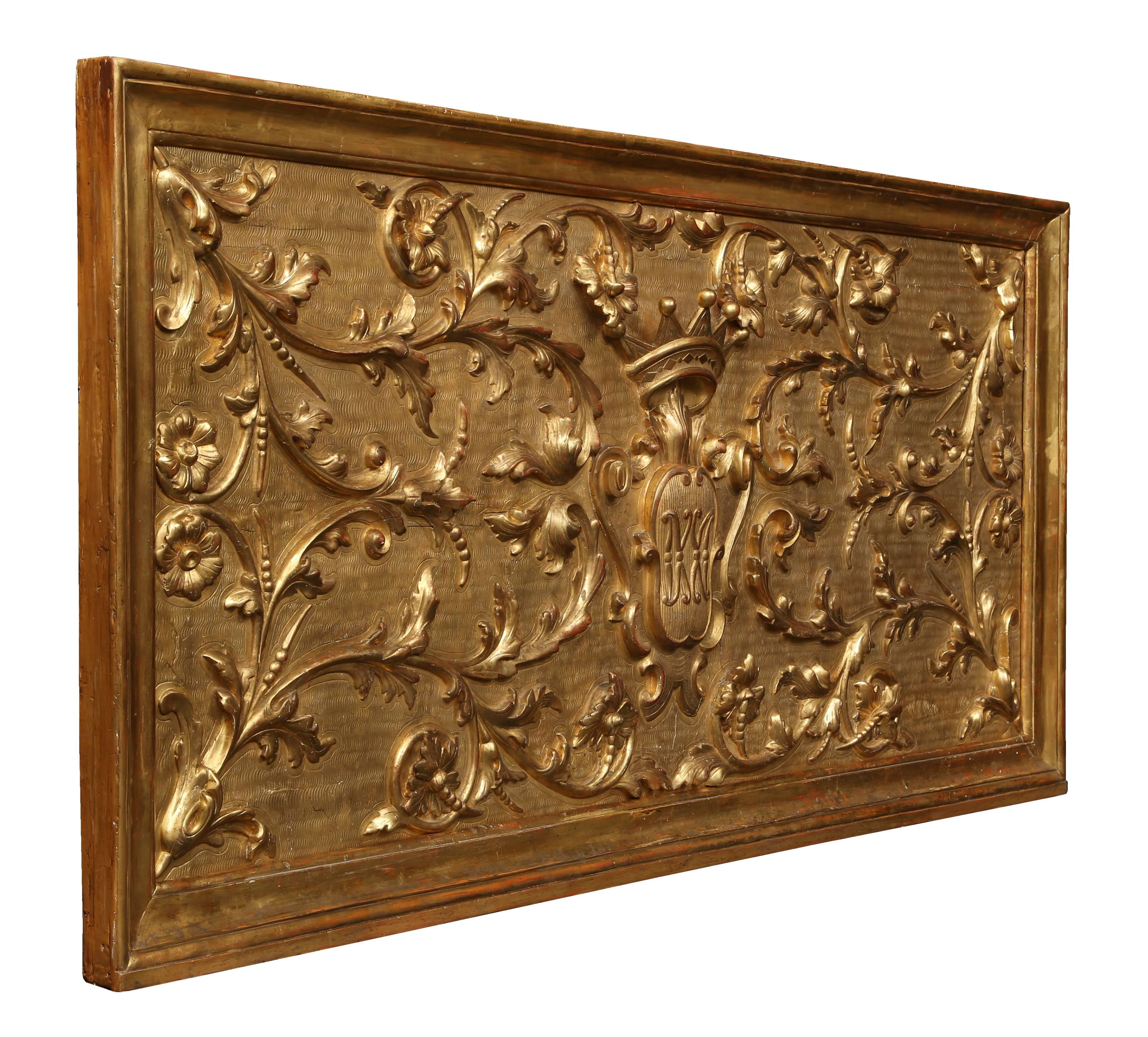 A spectacular and large-scale Italian 18th century extremely decorative giltwood family crest panel. This exquisitely carved giltwood panel is framed within a moulded border. The etched background is centered by a large family crest amidst scrolls
