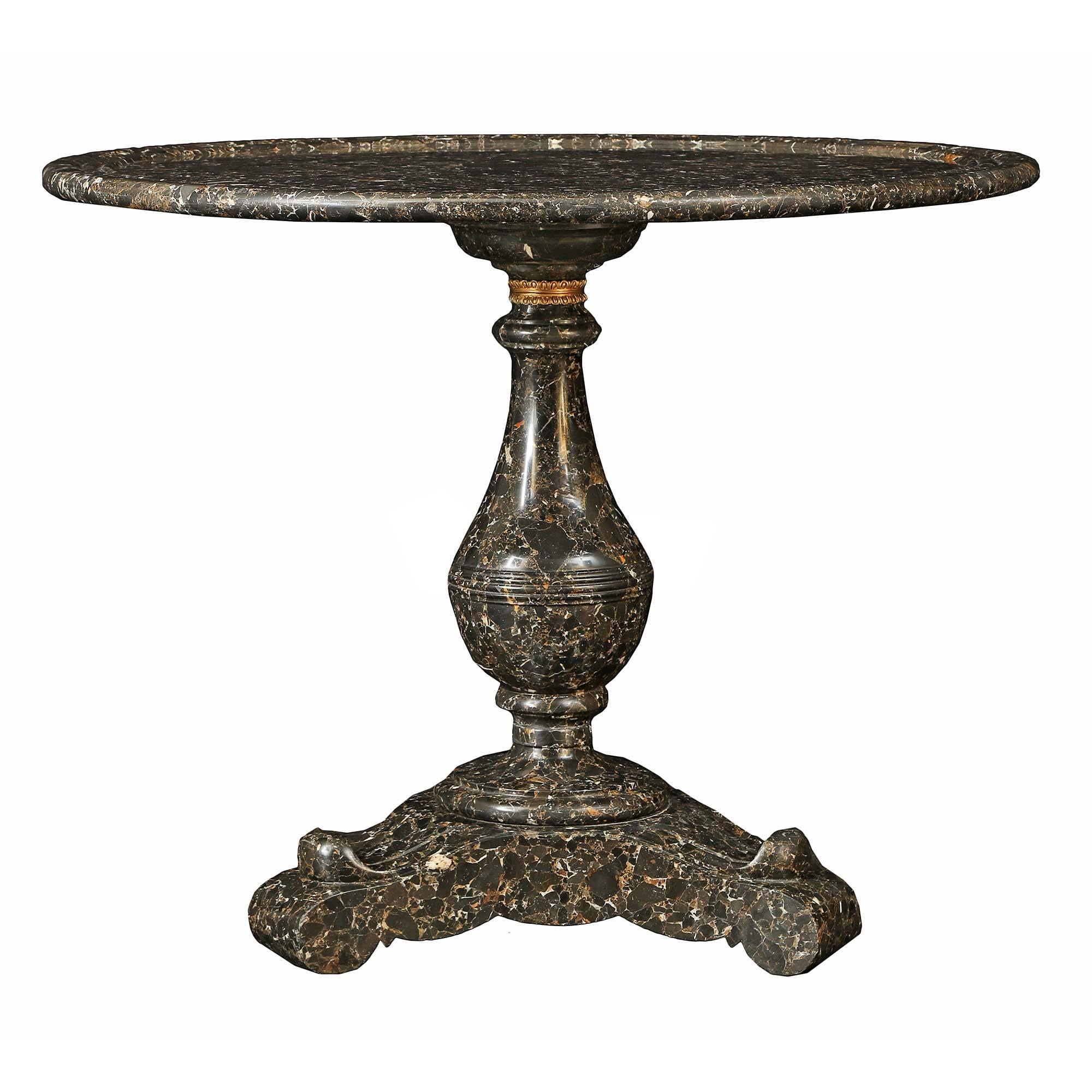 A stunning French 19th century Charles X Period solid Pyrénéese Portor marble center table. Raised by a triangular base with rounded corners and concave sides. Above is the baluster shaped central support with fluted design and finely chased