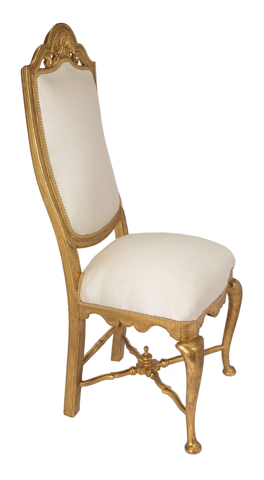 A magnificent complete set of twelve Continental 19th century Louis XV st. giltwood dining chairs. Each superb chair has straight back legs and cabriole legs at the front, all joined by an elegant  giltwood X stretcher centered by a finial. The