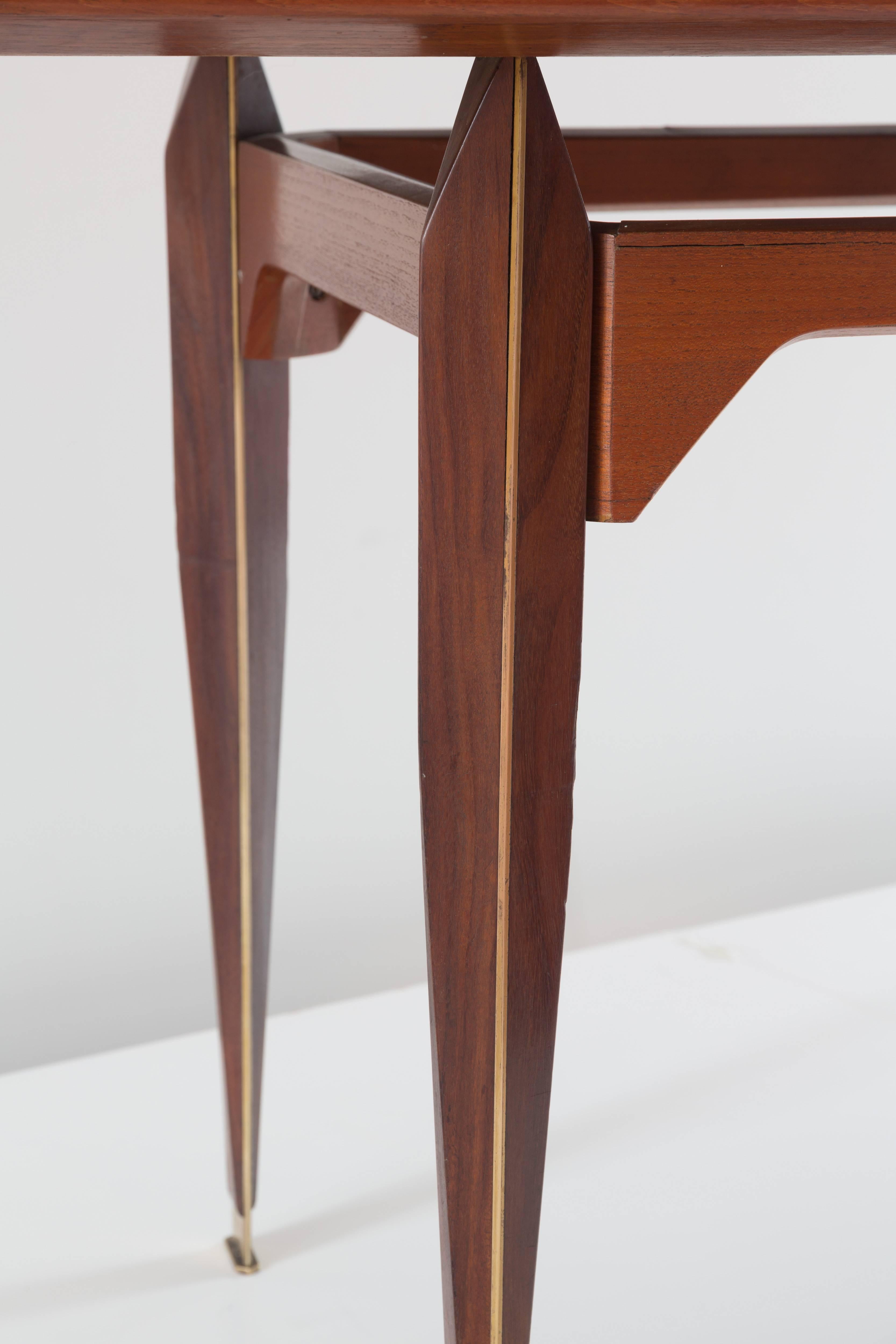 Important and rare dining table attributed to Franco Albini, 1953. 
Model similar to n. TL3 produced by Poggi. 
Probably a "unique example",
impressive contoured legs with brass insert and brass sabot. 
Teakwood and brass. 
Measures: