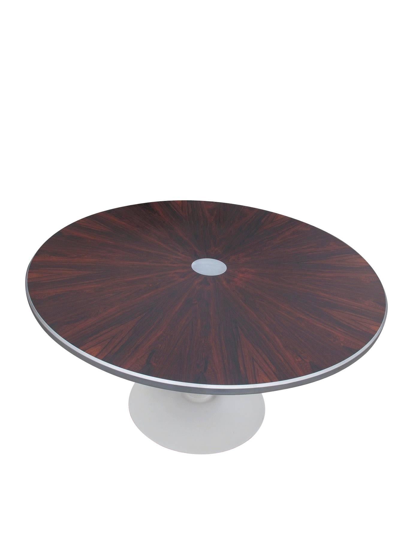 Danish dining table designed by Steen Ostergaard for Poul Cadovius. Stunning Brazilian rosewood arranged in a book-matched star pattern around an aluminum disc in center; silver aluminum trim on outer edge, raised on the original powder-coated