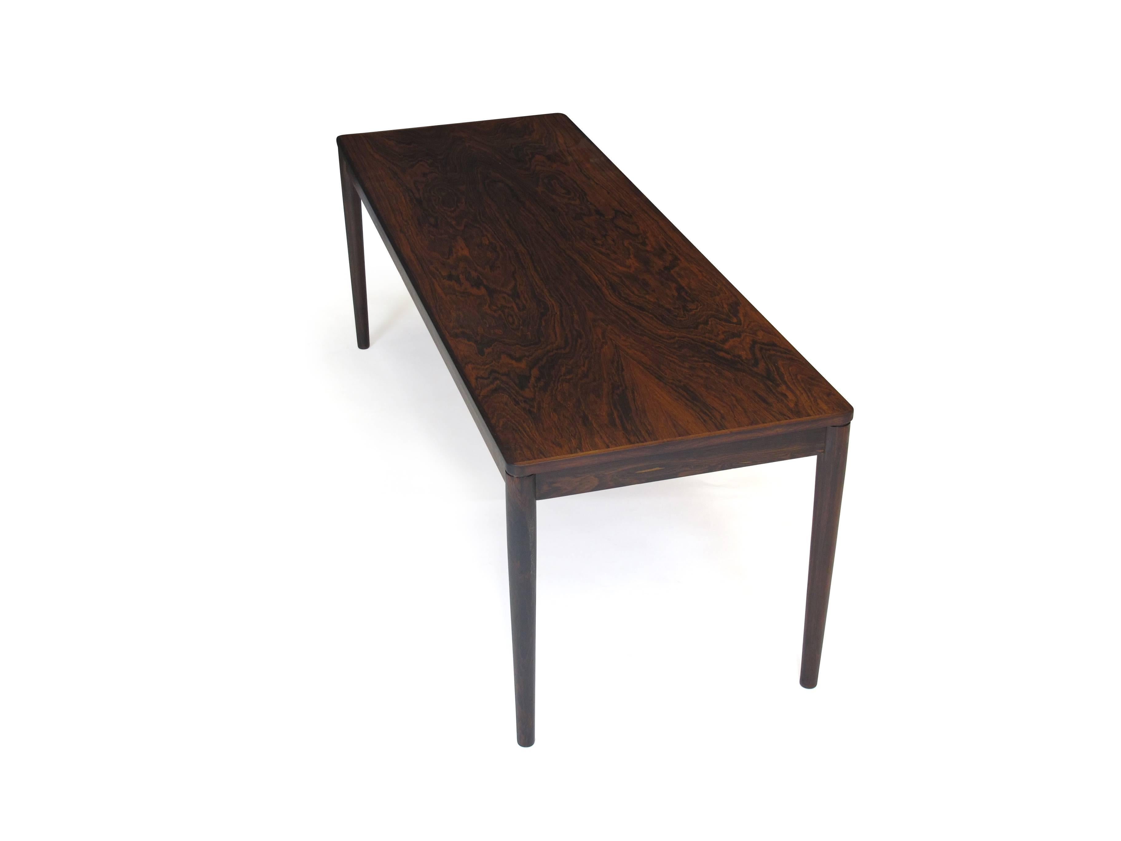 Midcentury Rosewood coffee table raised on round tapered legs.  Professionally restored and in excellent condition. 