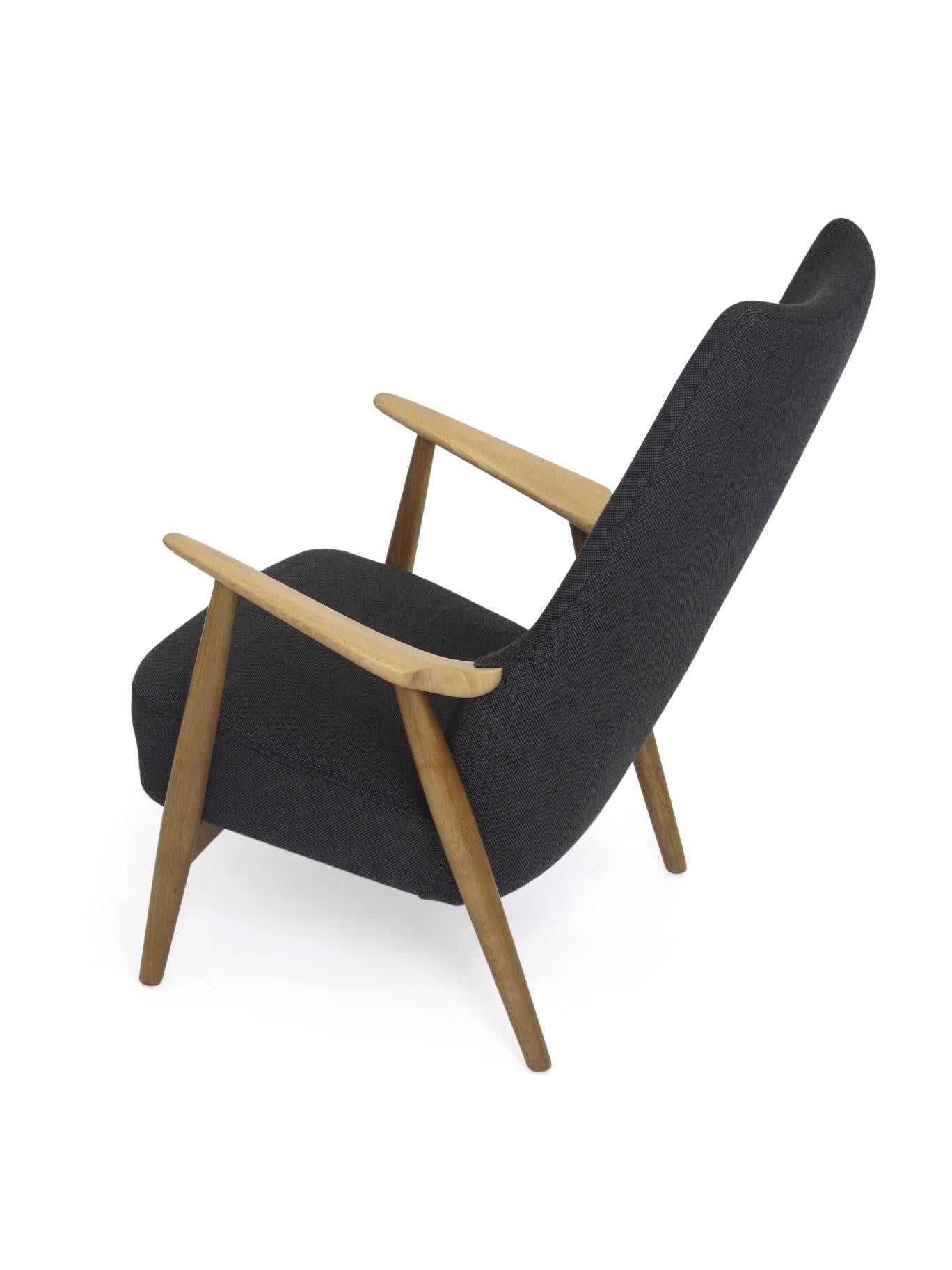 High back lounge chair designed by Hans Wegner features a white oak frame with beech arms, newly upholstered in a dark grey wool fabric with black leather button tufting. Chair is fully restored and in a excellent condition.