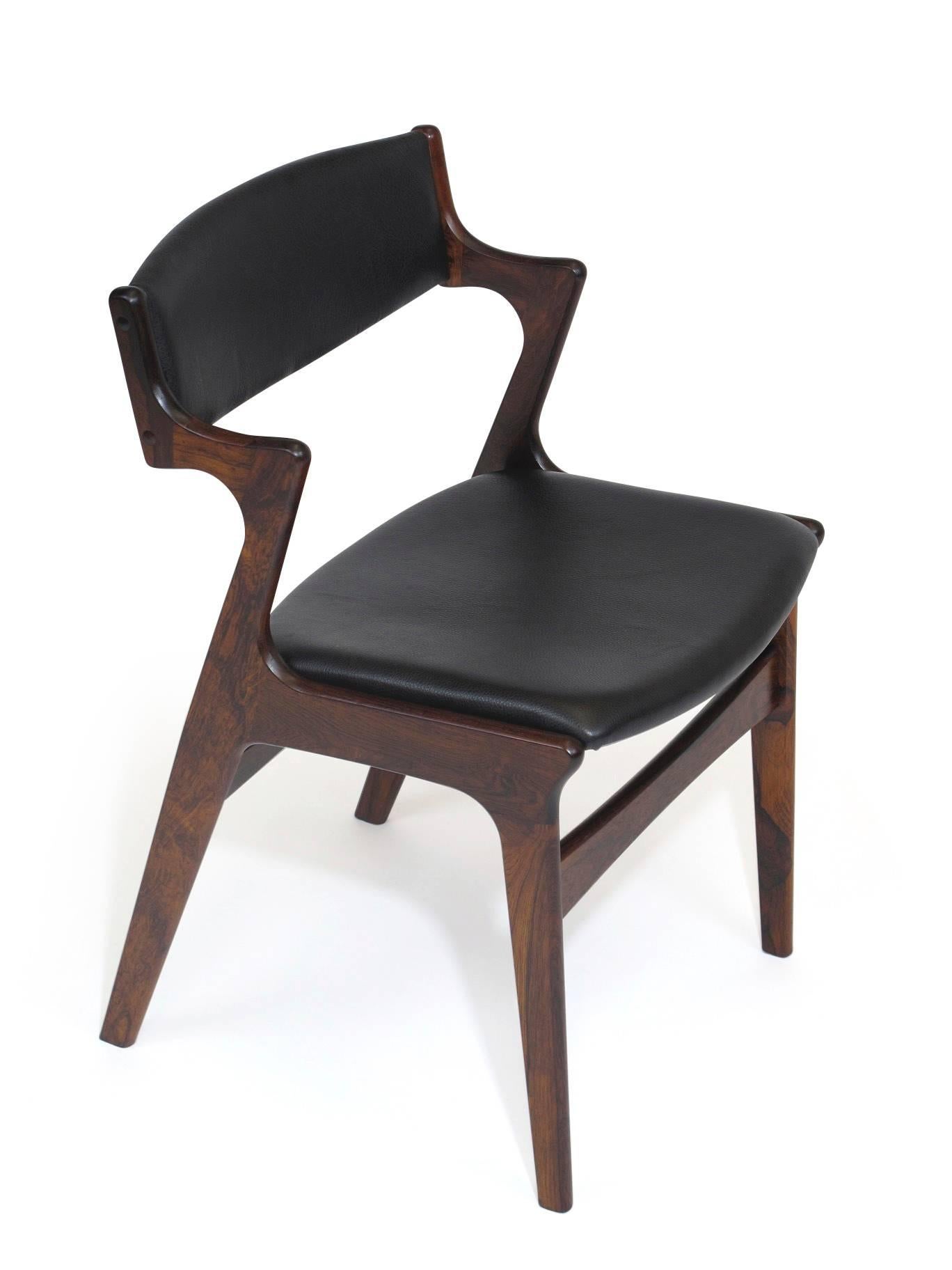 Mid-Century rosewood dining chairs manufactured by Nova Møbelfabrik, Denmark. The chairs feature solid rosewood frames with half arms, rich dark grain and exposed finger joinery. Newly upholstered in soft black leather. Fully restored and in an