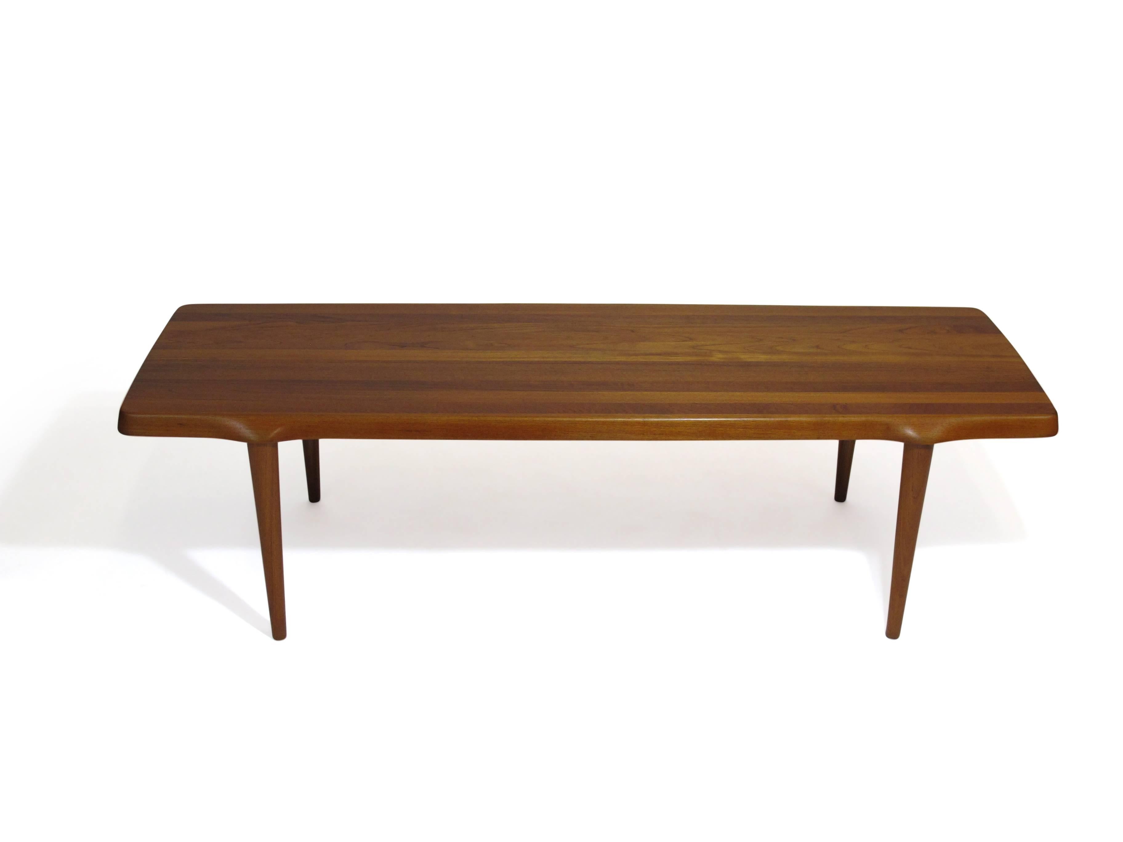Mid-Century Danish coffee table crafted of a solid teak plank with sculpted legs. 
Finely restored and in excellent condition.