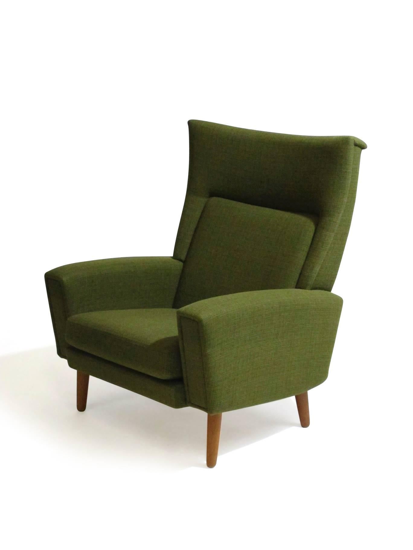 Mid-Century Scandinavian high back upholstered lounge chair in the manner of Illum Wikkelsø. Upholstered in the original green wool fabric with inner spring seat, raised on tapered teak legs.
 