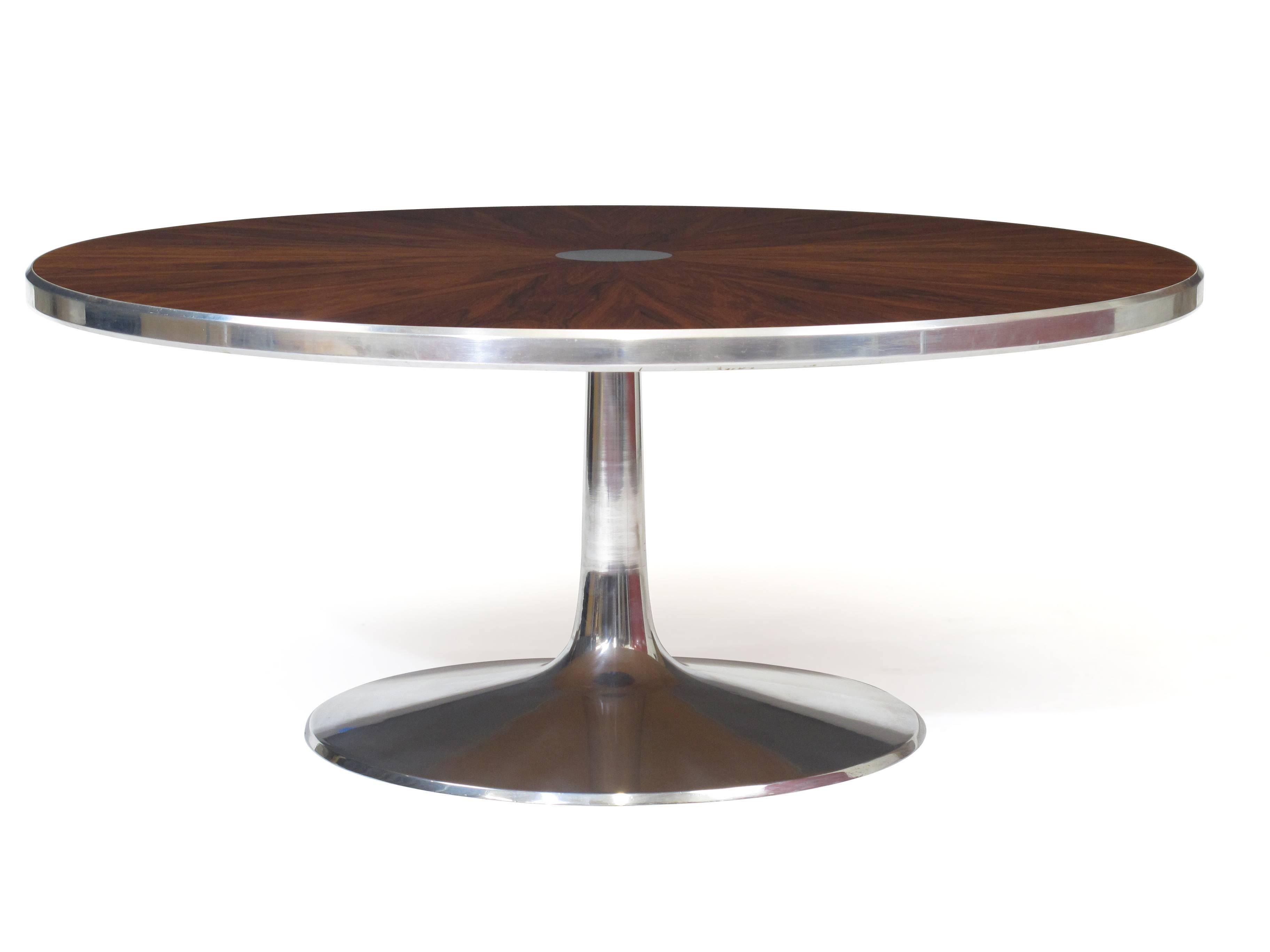 Mid-Century Danish coffee table designed by Steen Ostergaard for Poul Cadovius. Stunning rosewood arranged in a book matched star pattern around an aluminum disc in center, silver aluminum trim on outer edge, raised on a polished pedestal base.