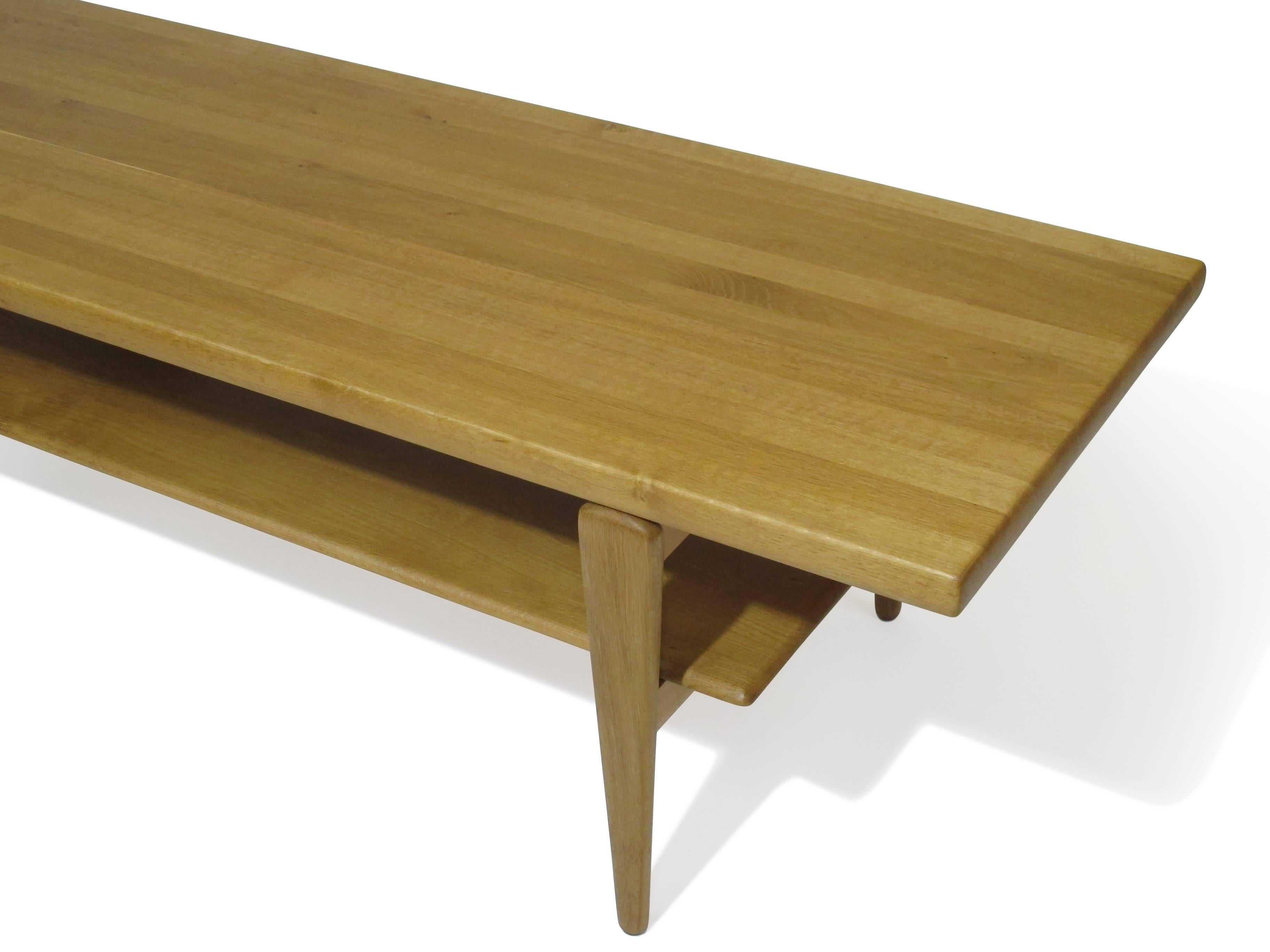 Mid-Century solid oak coffee table with shelf, crafted of solid oak planks. Raised on tapered legs. Finely restored and in excellent condition.
