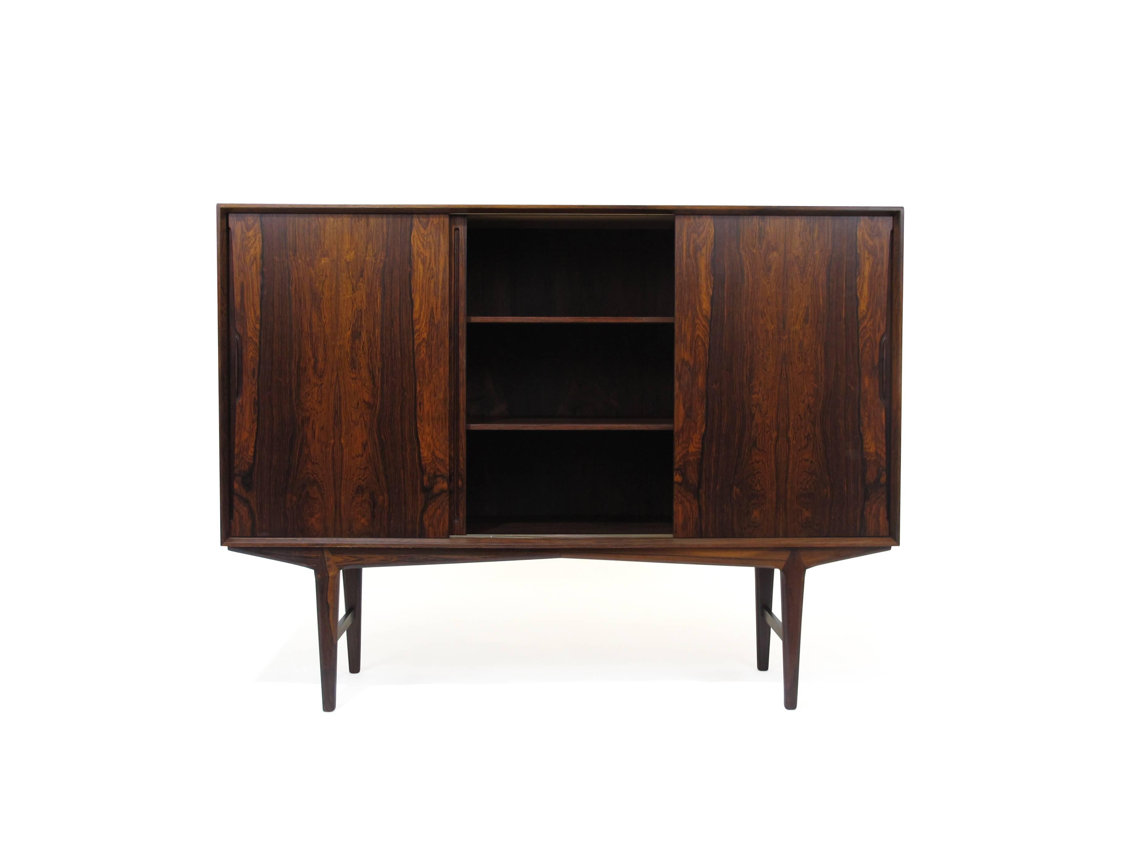 Rosewood sideboard with triple sliding doors with bookmatched graining and inset pulls, adjustable shelves, silverware drawers, raised on tapered legs.