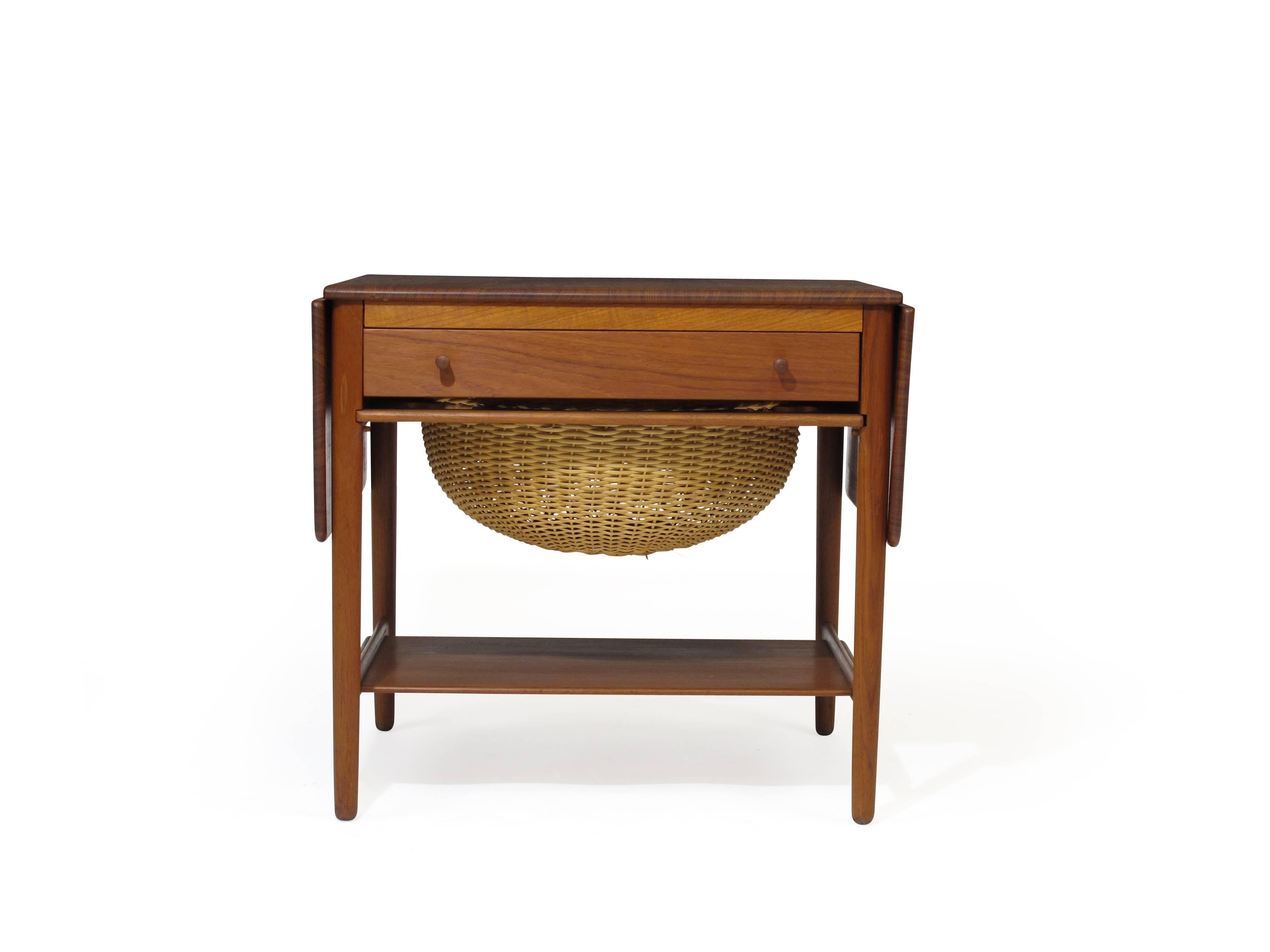 Mid-Century solid teak side table designed by Hans Wegner for Andreas Tuck, Model AT-33. Solid teak with two drop leaves, drawer on front and woven basket under for more storage.