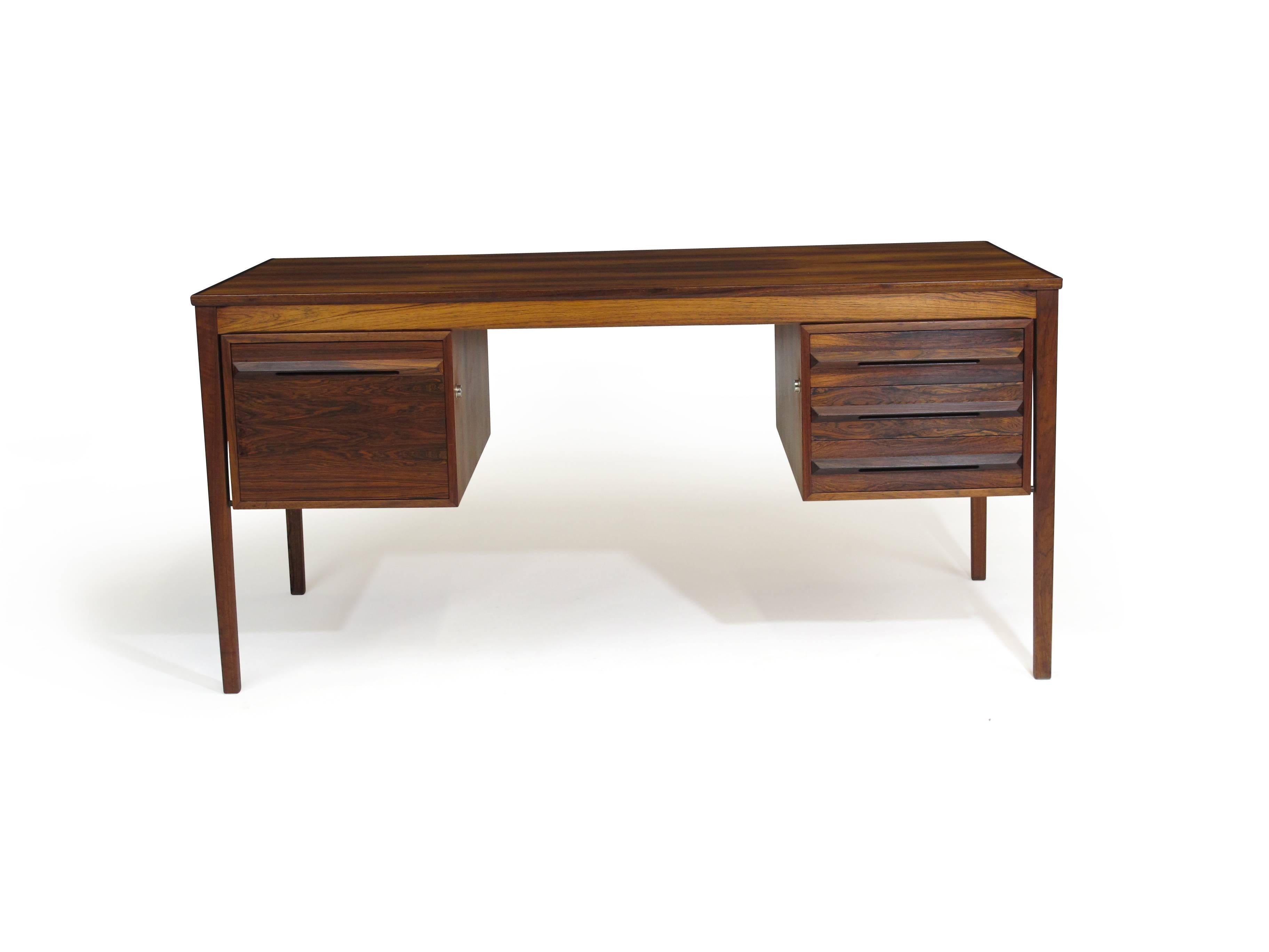 Midcentury Rosewood desk by Haug Snekkeri, Norway with filing cabinet on left side, and bank of three drawers on right, raised on square tapered legs. The desk has a finished back and can be placed in the middle of a room. Newly restored and in