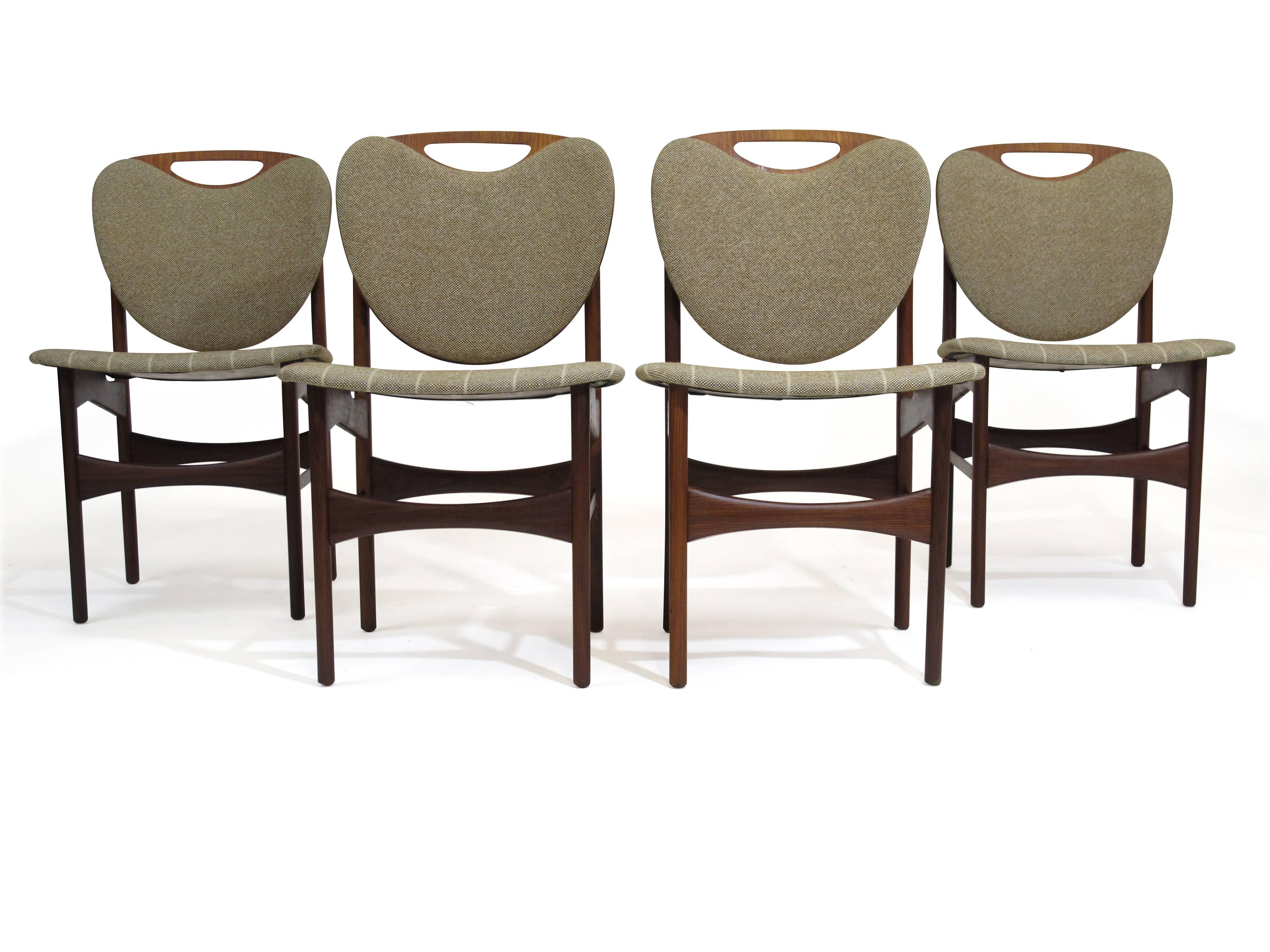 Four Danish teak dining chairs with shield shaped back in original vintage fabric. 
Custom upholstery available upon request.