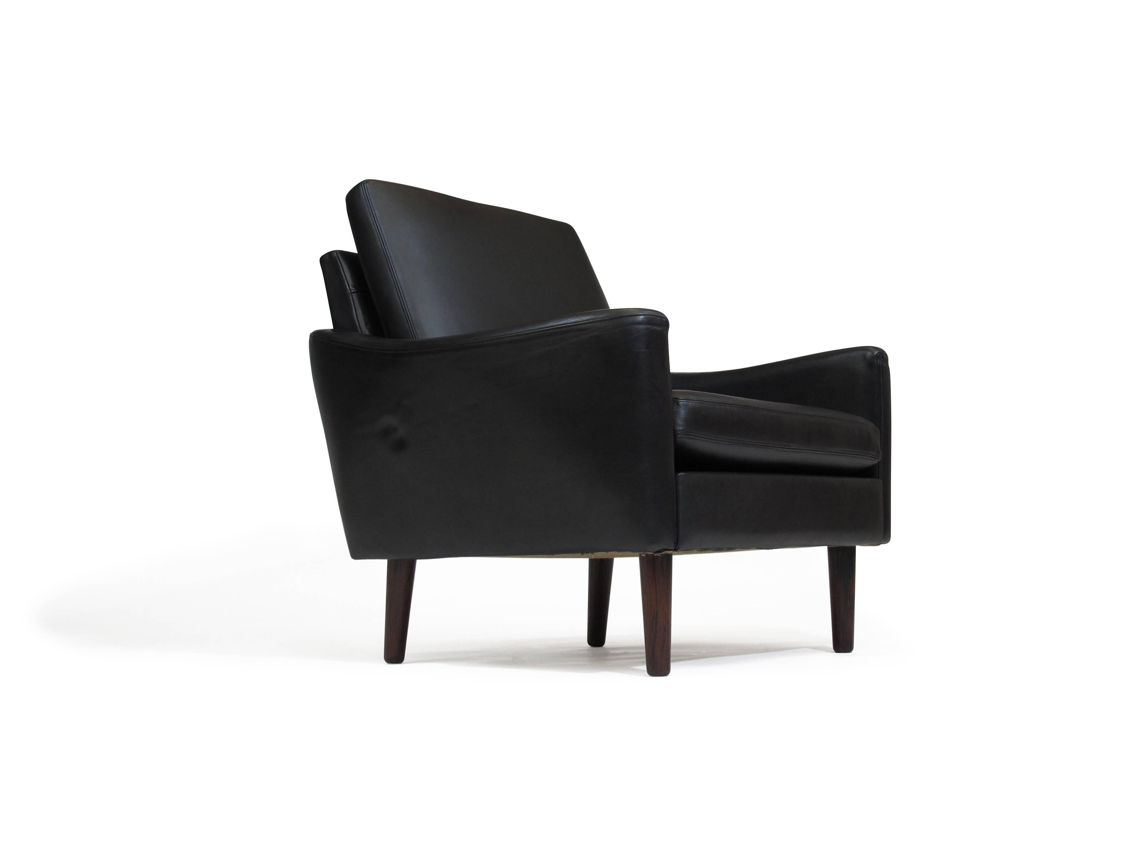 Pair of midcentury black leather lounge chairs crafted of a solid wood frame upholstered in the original vintage black leather with newly upholstered seat and back cushions.