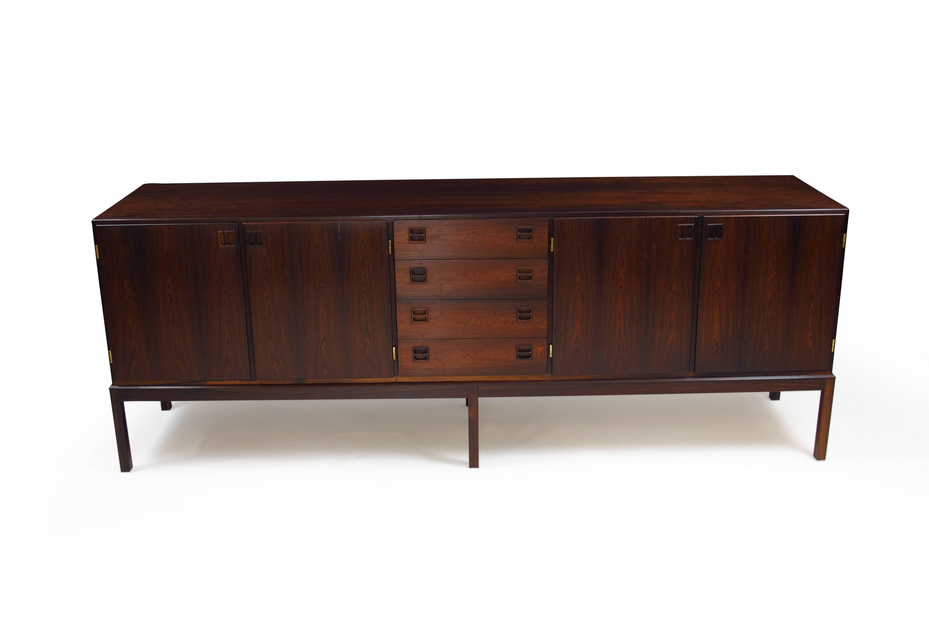 Mid-century Brazilian Rosewood credenzaDesigned by Johannes Andersen for Bernhard Pedersen & Son, Denmark. Model 160, features dark Brazilian rosewood with book-matched grain and recessed square pulls. The cabinet has four drawers in center, cabinet