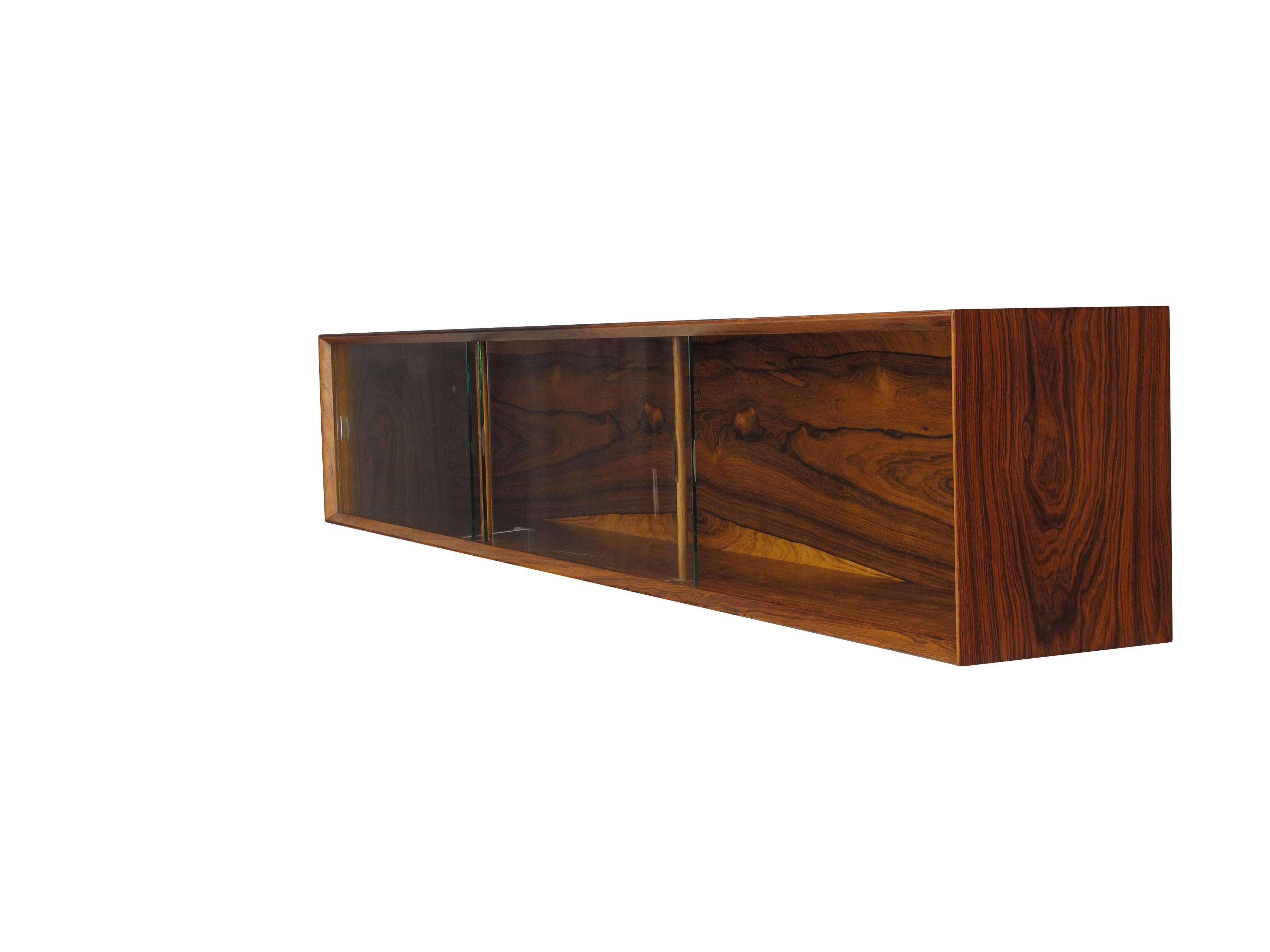 Finely crafted Midcentury rosewood wall mount credenza with mitered edges and three sliding glass doors. Additional images available upon request.