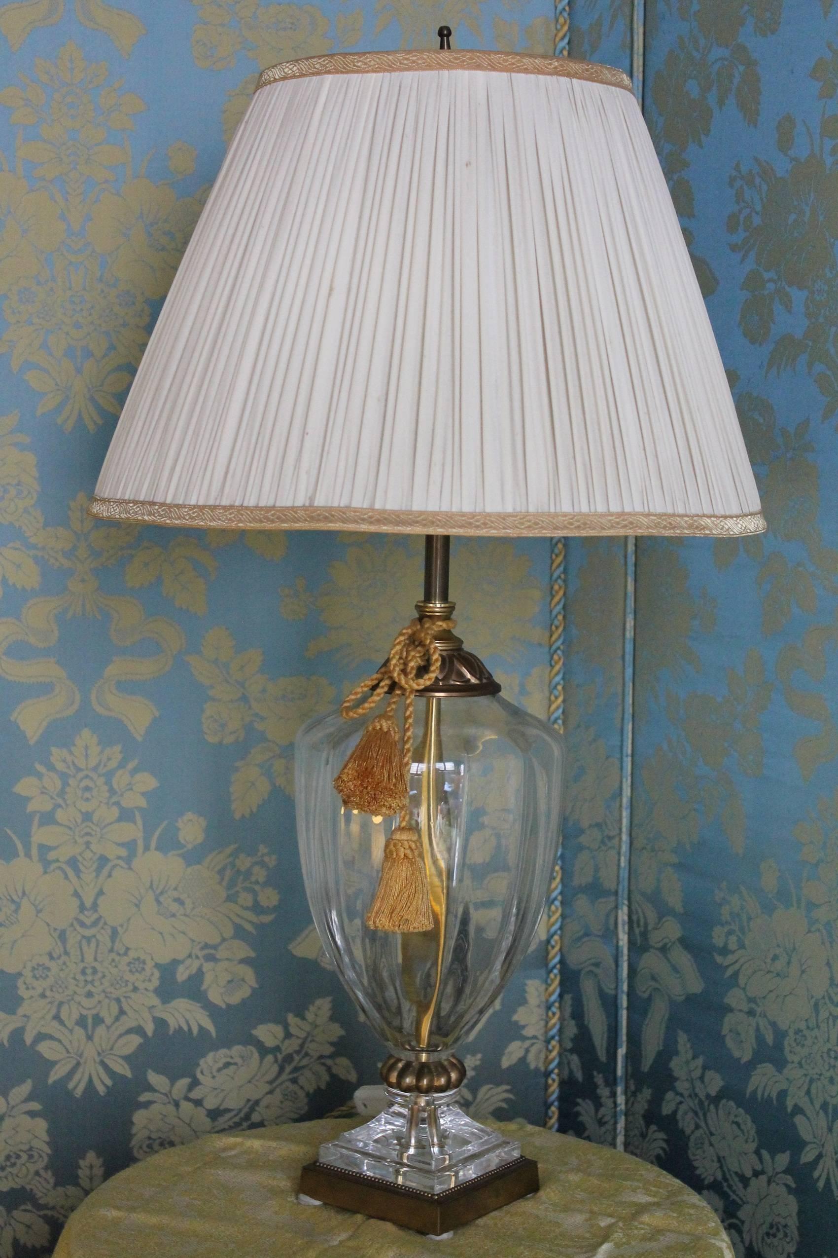 An Italian two lights vintage 1950s sparkling, fluted, solid crystal table lamp with gilded brass accents resting on a square beaded brass gold colored base. This sophisticated Mid-Century Modern piece has a traditional-shape and features hand-cut