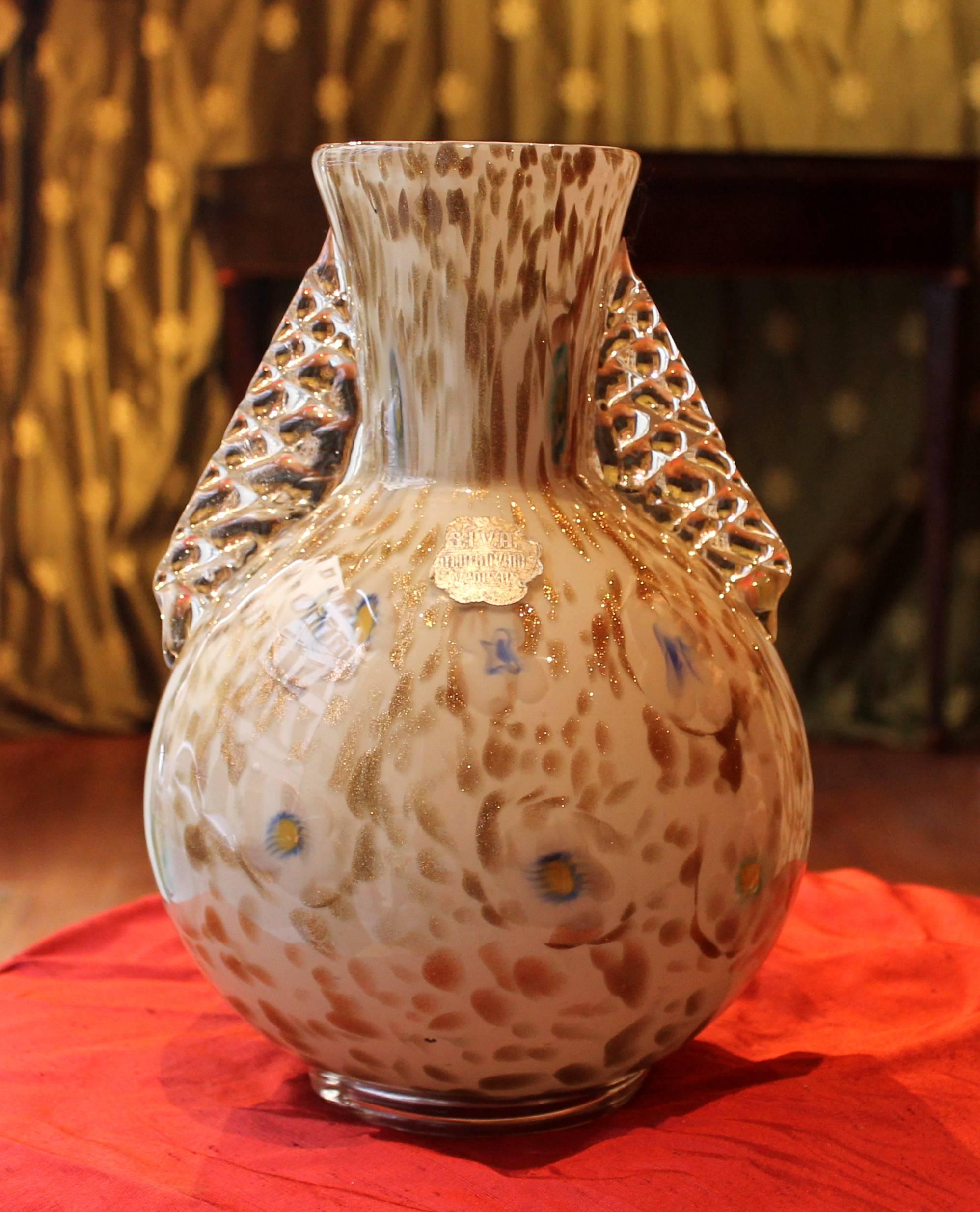 Ce magnifique vase italien de Murano soufflé à la main, datant du milieu du siècle dernier, présente un élégant fond blanc laiteux avec des mouchetures dorées et des motifs floraux bleu clair. Il porte l'étiquette originale de la manufacture de
