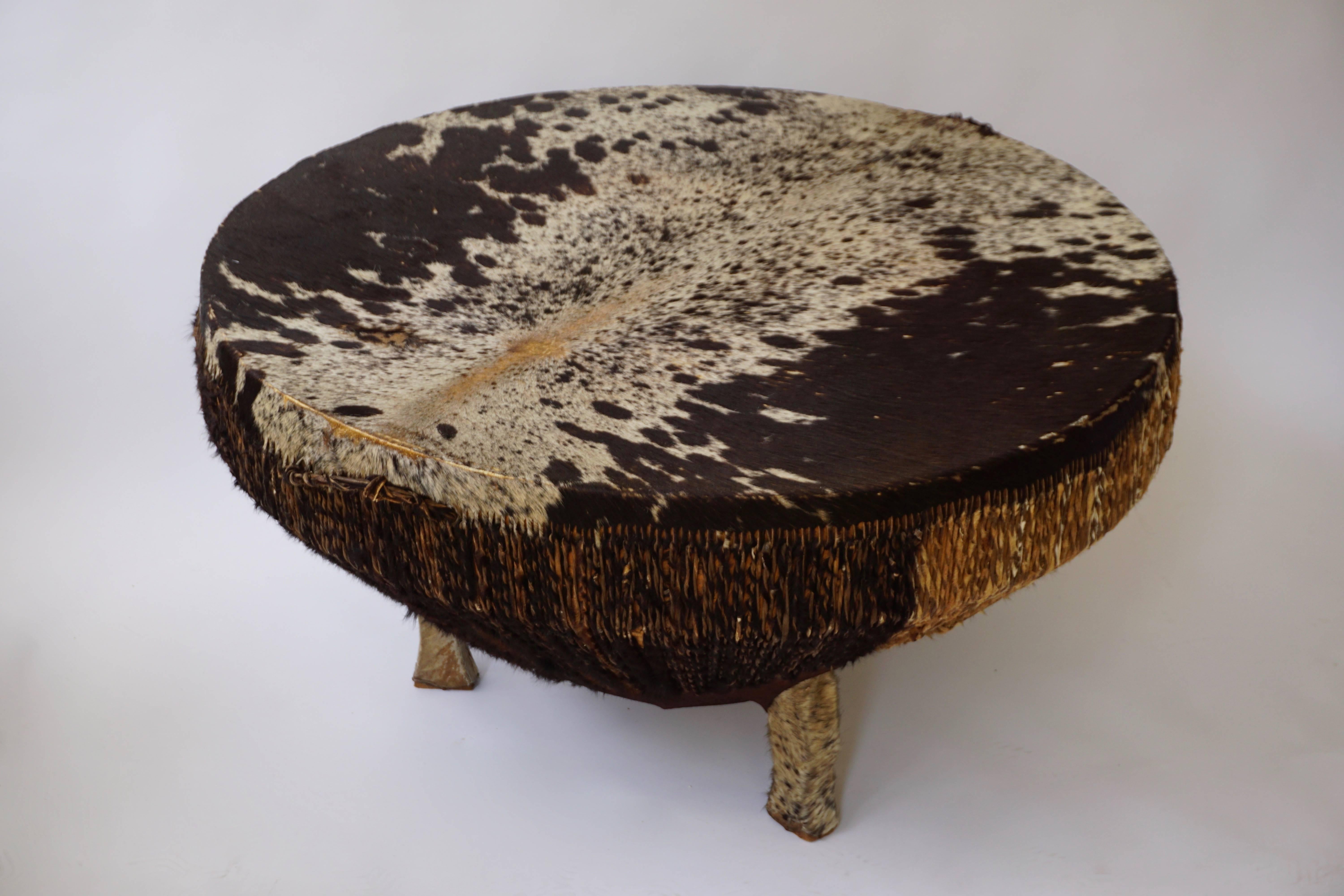 An African animal skin hide covered drum coffee table, with twisted hide down the sides and hide covered feet, circa 1950.
