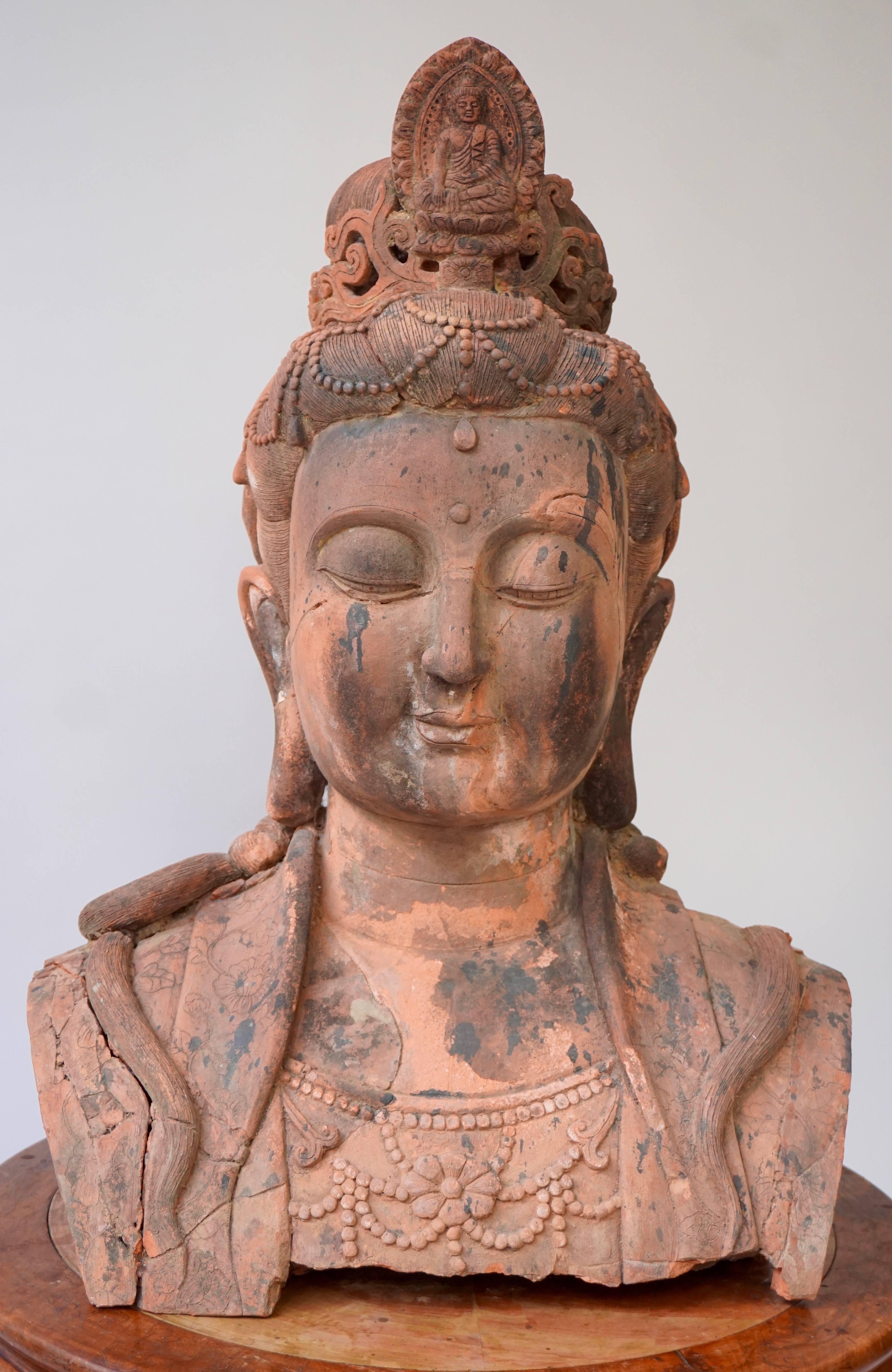 A massive larger than life terracotta buddha bust of Guan Yin,
China, early 20th century.
Broken and restored with wear and tear from enduring exposure to the elements.
Size: 75 cm high.
Weight: 40 kg.

Guanyin, Kwanyin, Guanshiyin or Guanyin Pusa