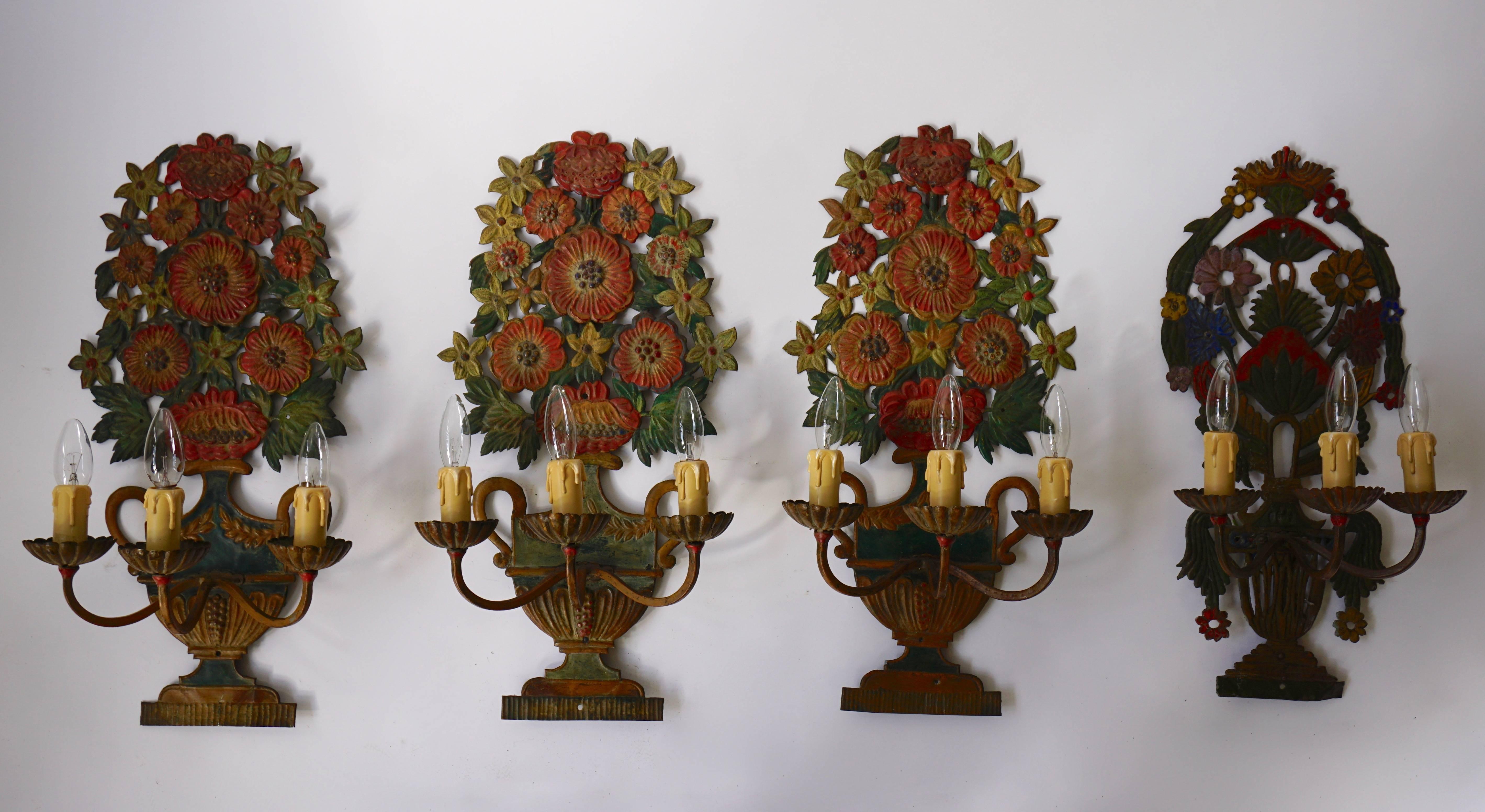 A collection of three similar and one different painted iron three – light wall sconces, shaped as Regency vases filled with flowers: 20th century.
Size of the three wall lights: 58 cm height.
Width 31 cm.
Depth 20 cm.

Size of the other wall