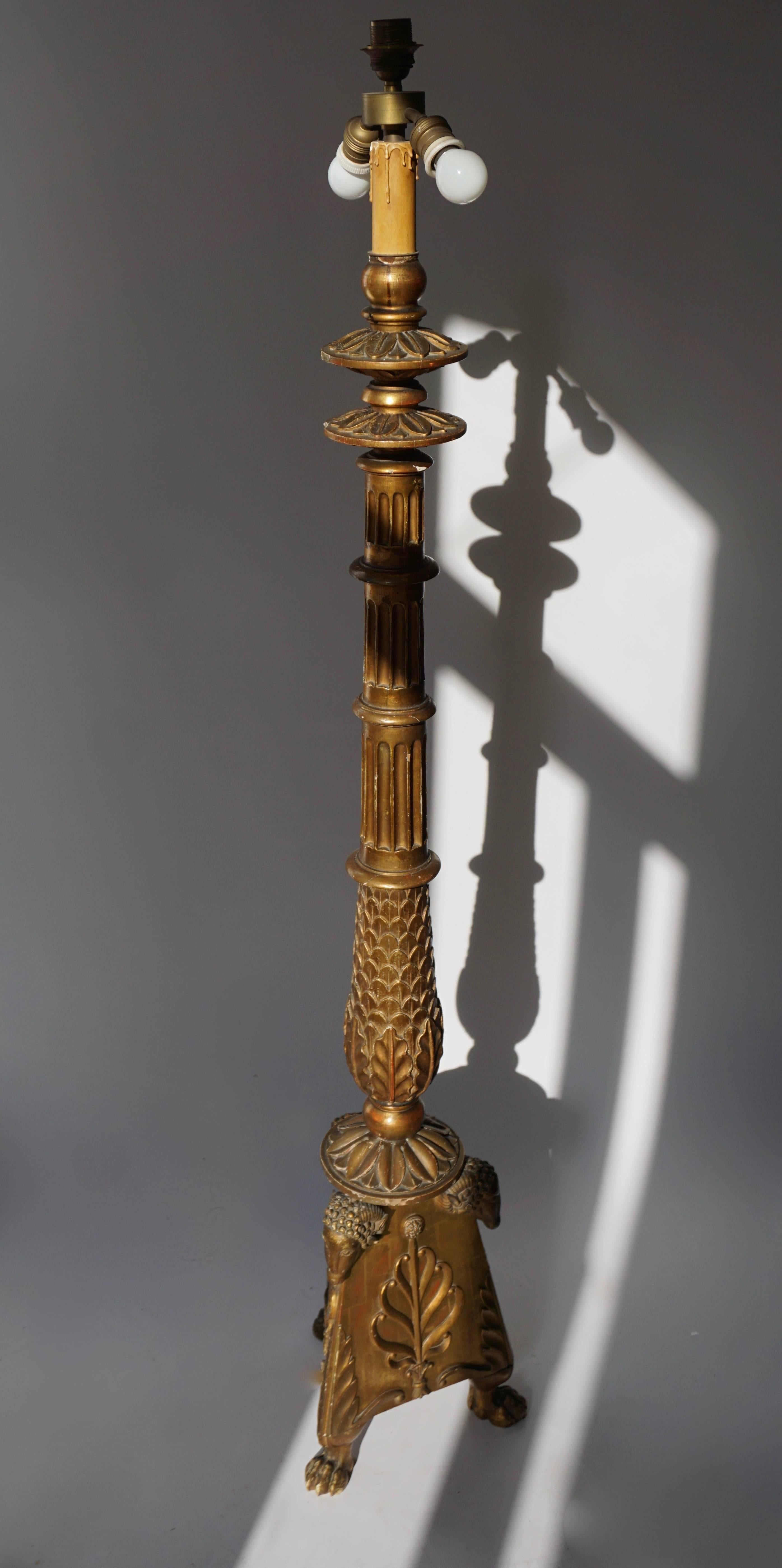 A candelabrum shaped carved giltwood lamp stand in the Greek revival neoclassical style, resting on claw feet, the base decorated with protruding ram’ s heads and palmettes, mid-20th century.

The height is without lampshade is 165 cm. Diameter is