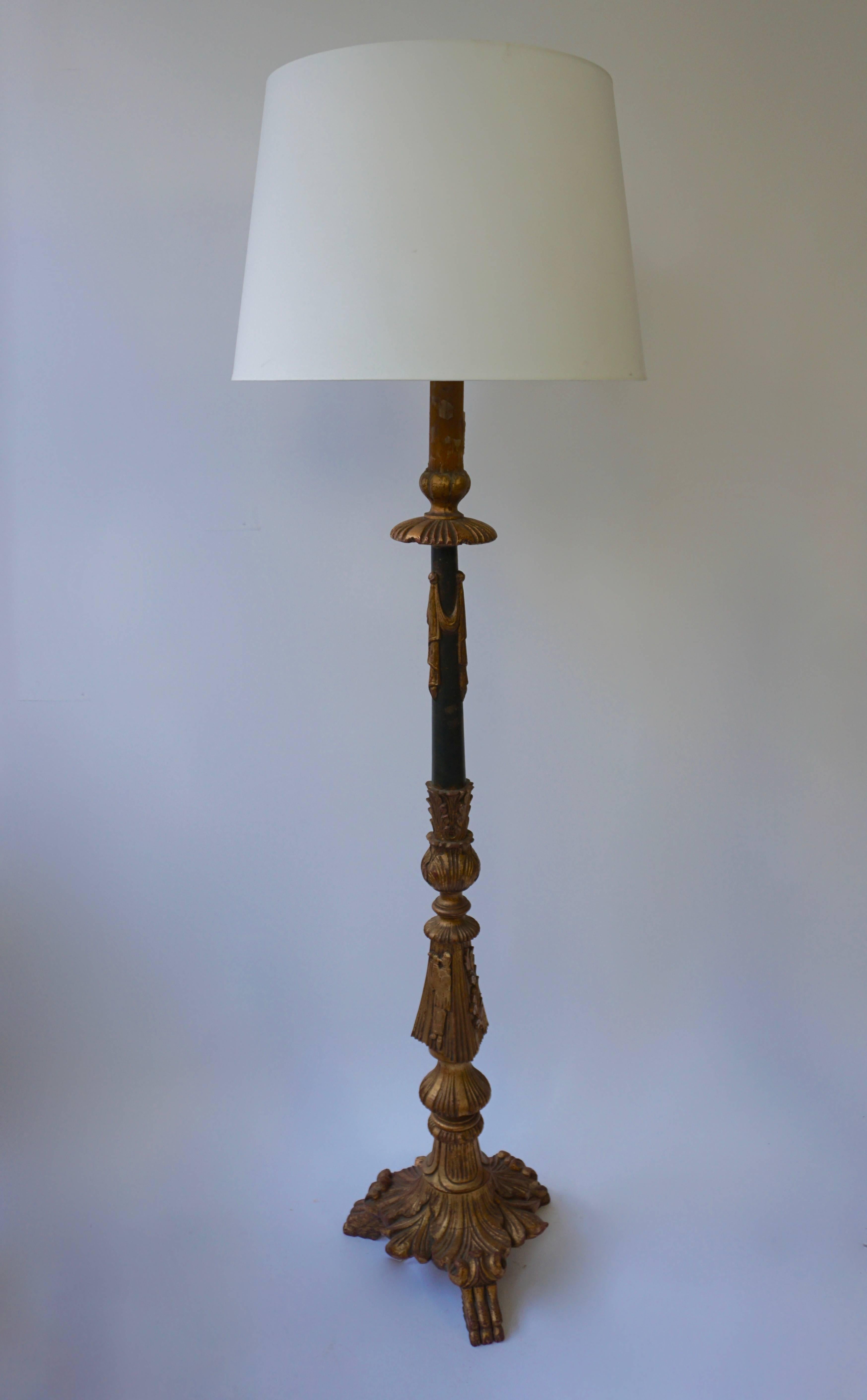 A candelabrum shaped carved, gilt and painted wood lamp stand in the neoclassical style, mid-20th century.

Height without shade: 168 cm.
Diameter: 38 cm.
Height with shade: 177 cm.
Diameter shade: 54 cm.